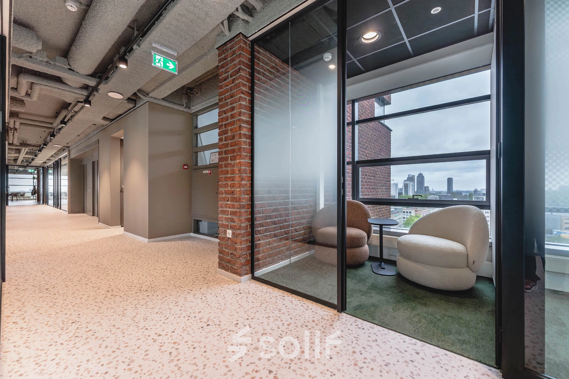Modern office space with brick walls, glass partitions, and lounge seating at Joop Geesinkweg 201, Amsterdam Amstel Business Park, ideal for office space rental.