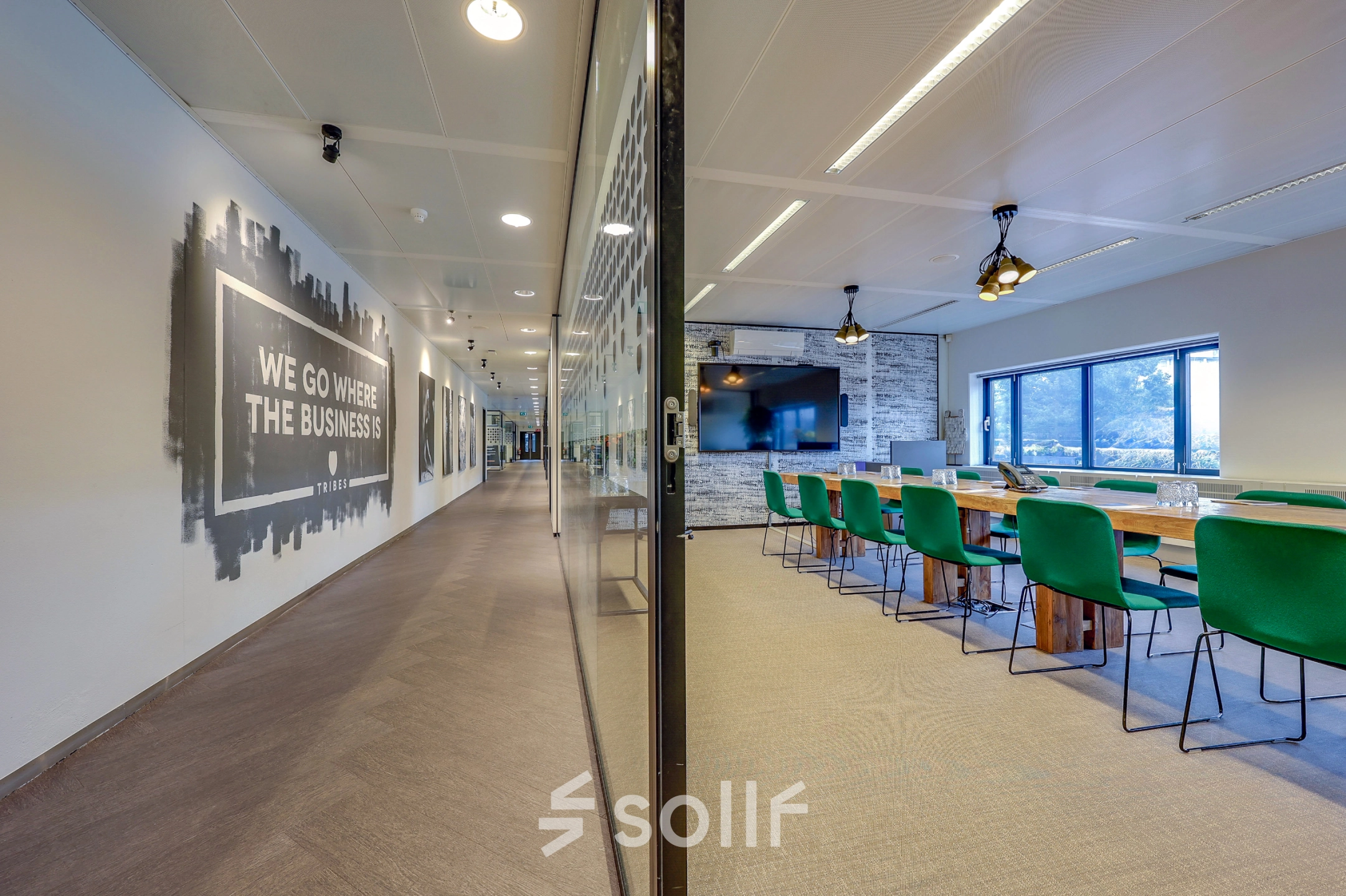 Spacious office space at Prins Bernhardplein 200, Amsterdam Amstel, with a conference room featuring green chairs and a large table, ideal for meetings. Perfect for office space rental.