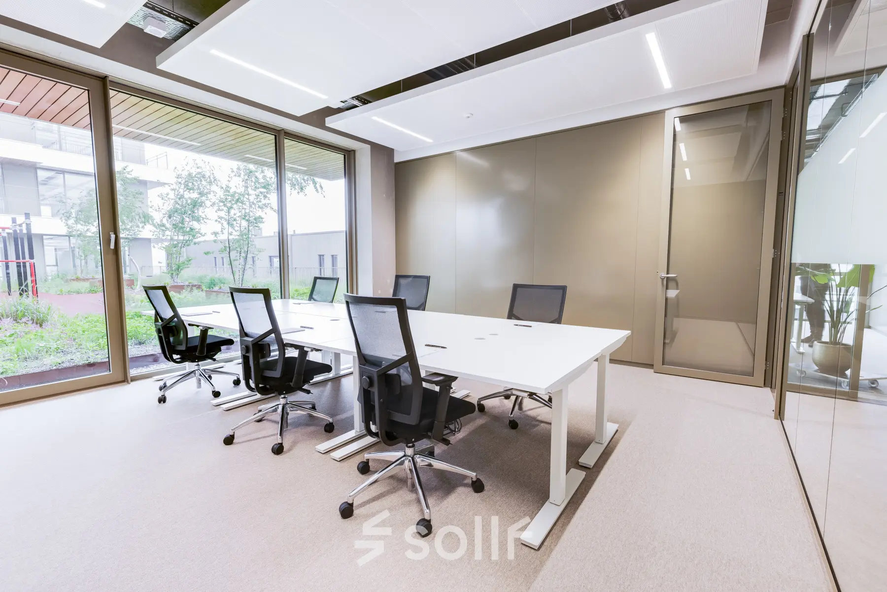 Modern office space rental in Amsterdam Amstel with a large table and chairs, featuring glass walls and natural light.