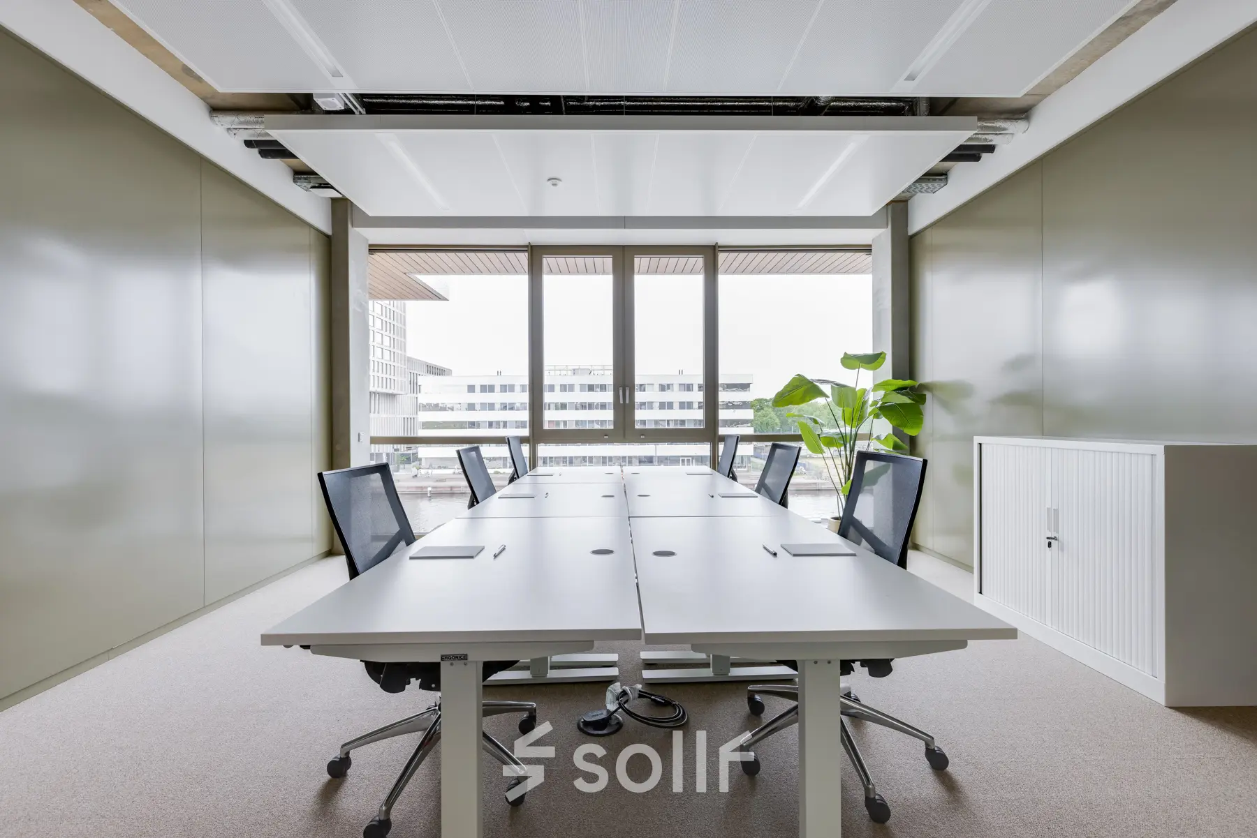 Modern office space in Amsterdam Amstel with large windows, conference tables, and sleek chairs. Ideal for office space rental.