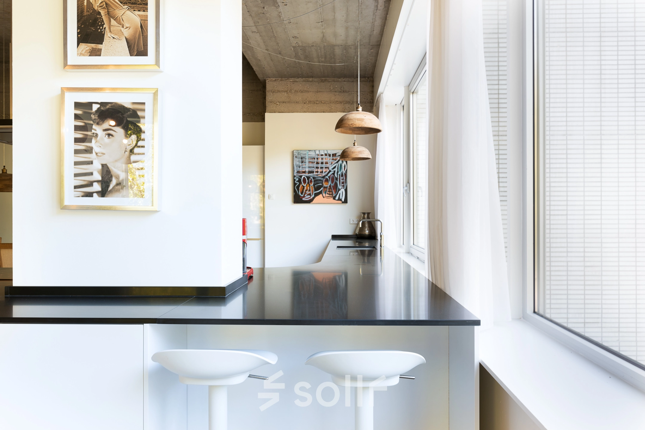 Stylish office interior at Teilingen 1 in Amsterdam Buitenveldert, featuring a sleek counter with two modern bar stools under pendant lights, perfect for relaxed breaks. Ideal for office space rental.