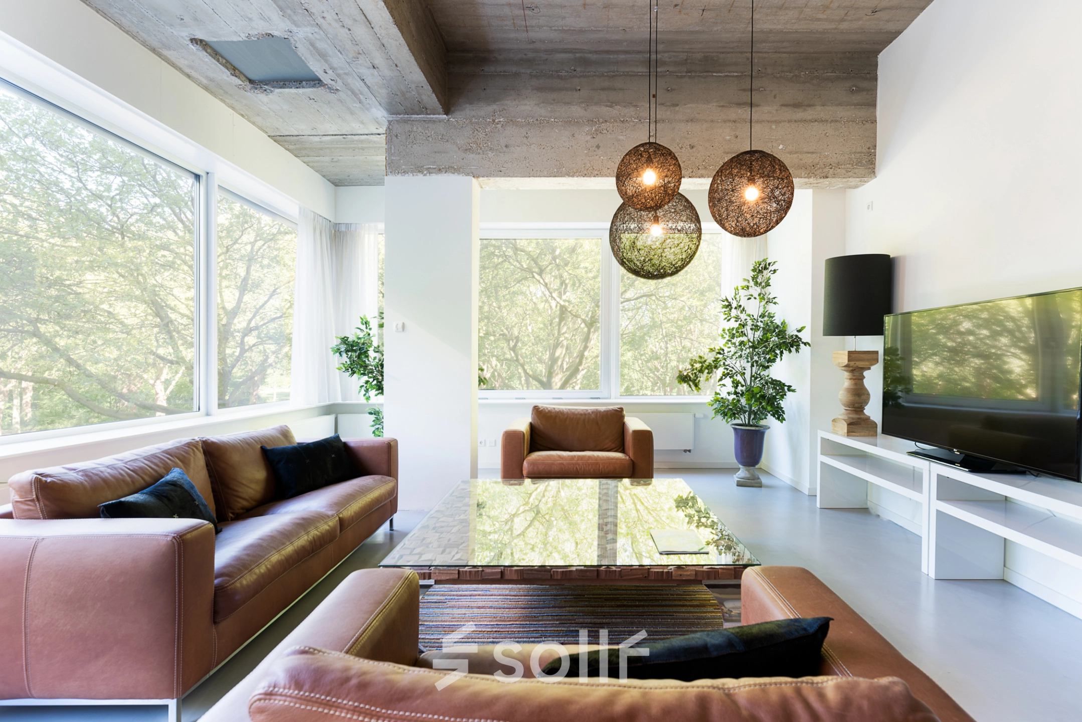 Spacious office lounge at Teilingen 1 in Amsterdam Buitenveldert, featuring leather seating, modern decor, and large windows overlooking greenery. Ideal for office space rental with a welcoming ambiance.
