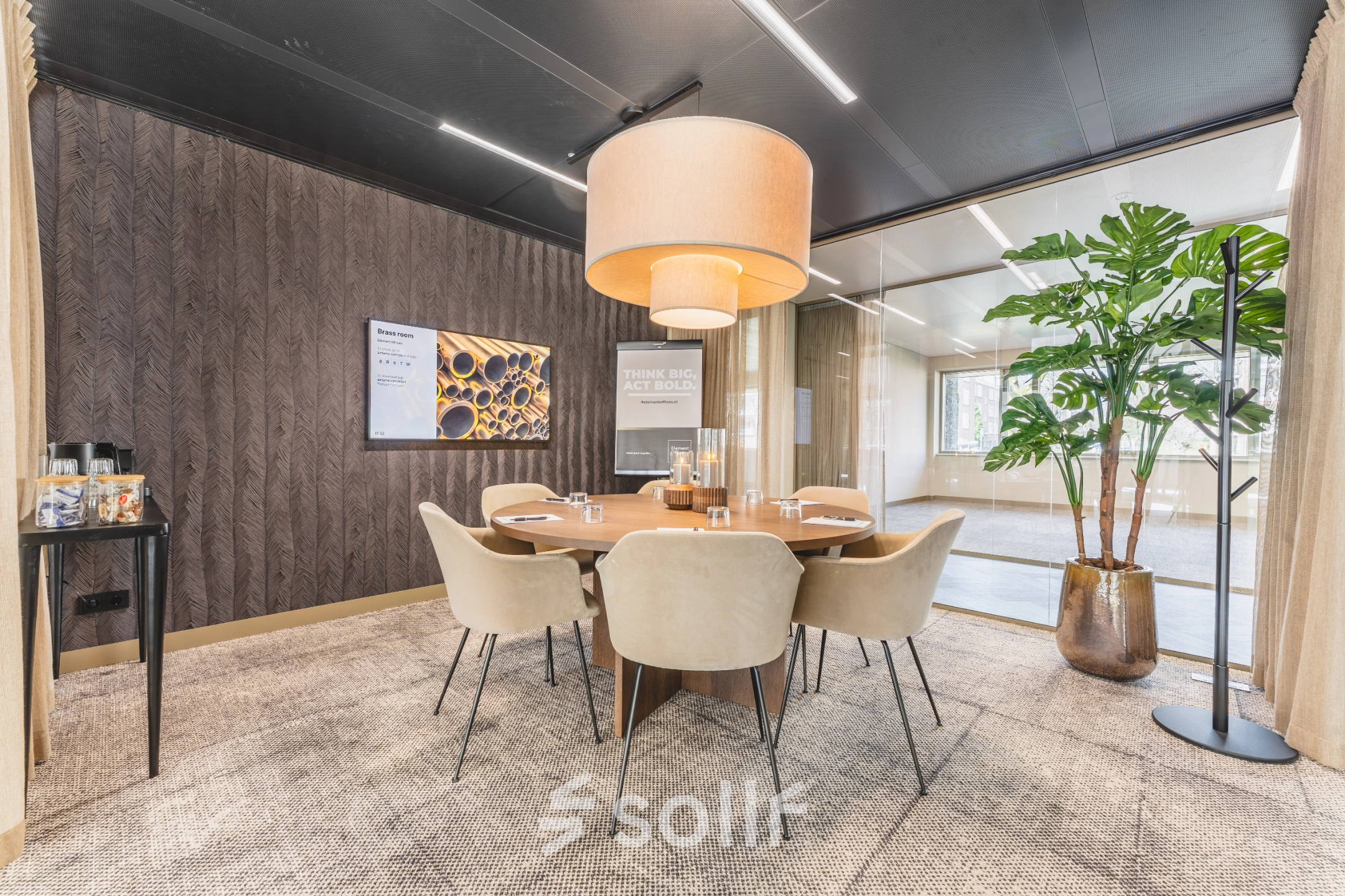 Modern office space for rent at Walborg 2A, Amsterdam Buitenveldert, featuring a meeting room with a round table, chairs, a large plant, and stylish lighting.