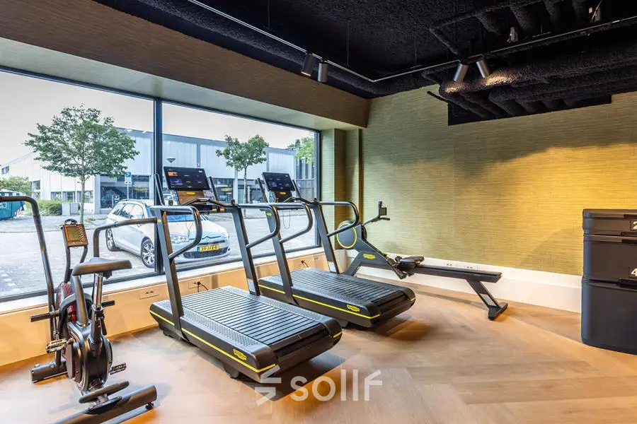 Office space rental gym area with treadmills and exercise bikes by a large window at Zwaansvliet 1, Amsterdam Buitenveldert.