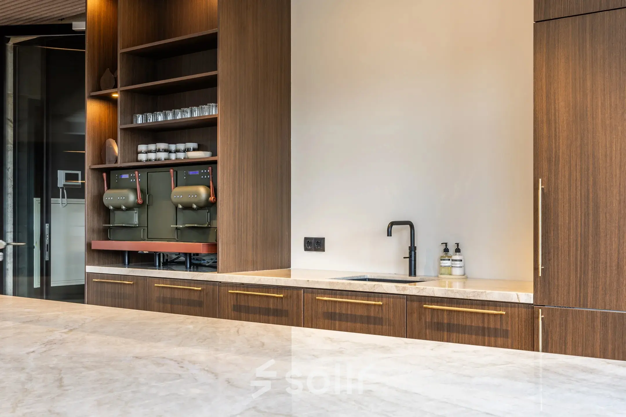 Modern office pantry with wooden cabinetry, marble countertops, coffee machines, and a sink at Zwaansvliet 1, Amsterdam Buitenveldert; perfect for office space rental seekers.