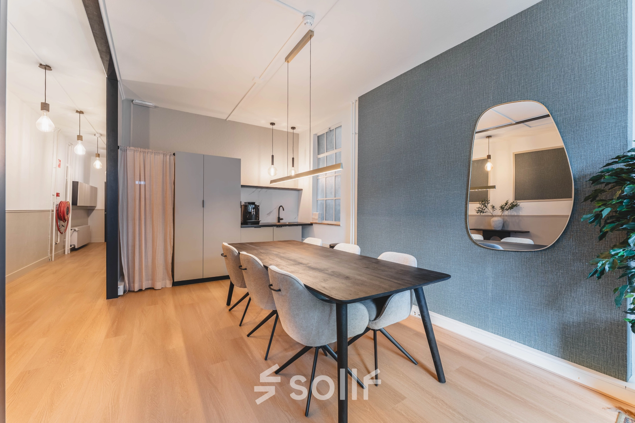 Interior view of a furnished office space rental on Herengracht 221, Amsterdam Canal Belt, featuring a conference table with chairs and a kitchenette.