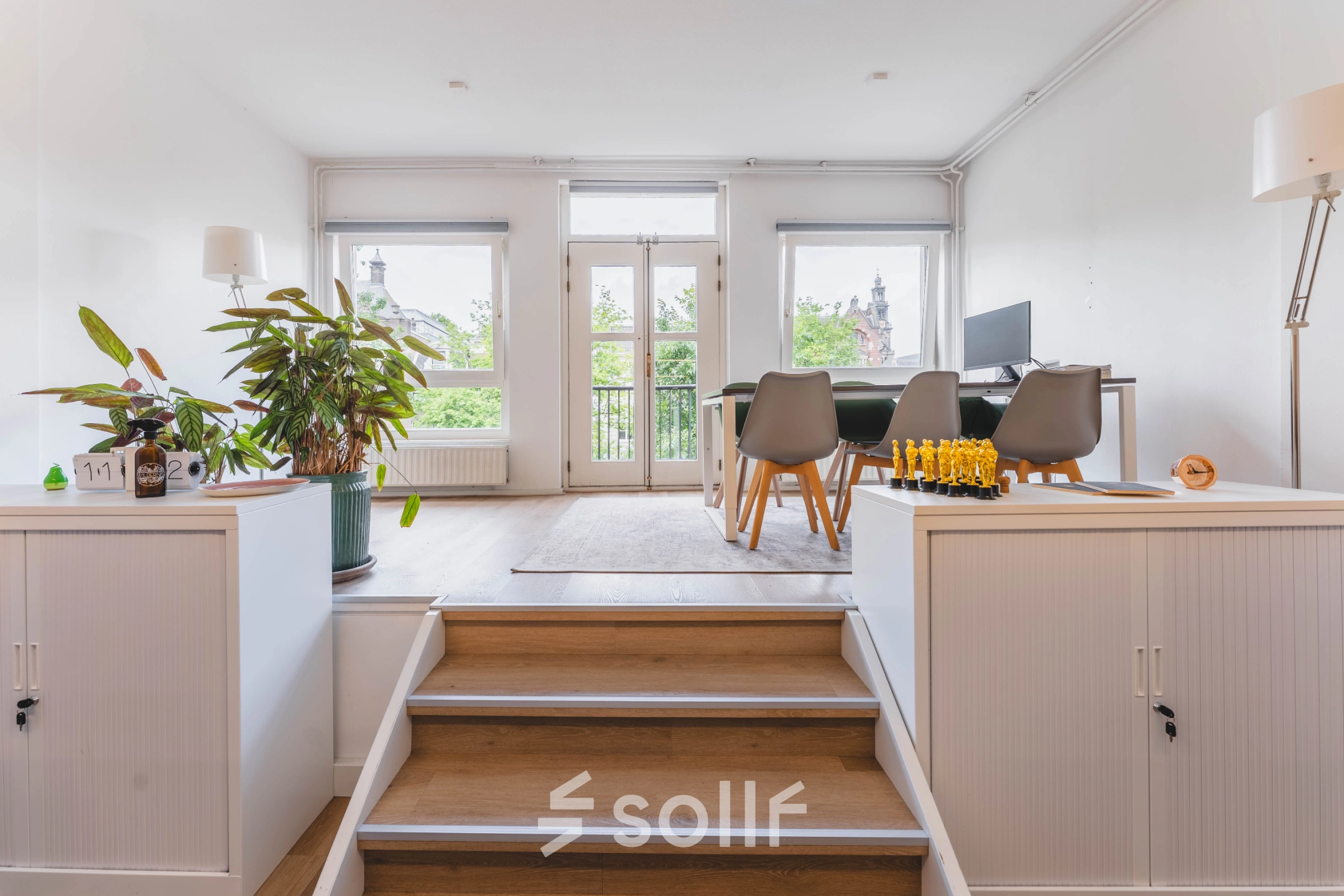 Bright office space at Herengracht 221 in Amsterdam Canal Belt with large windows, modern furniture, and green plants. Ideal for office space rental.