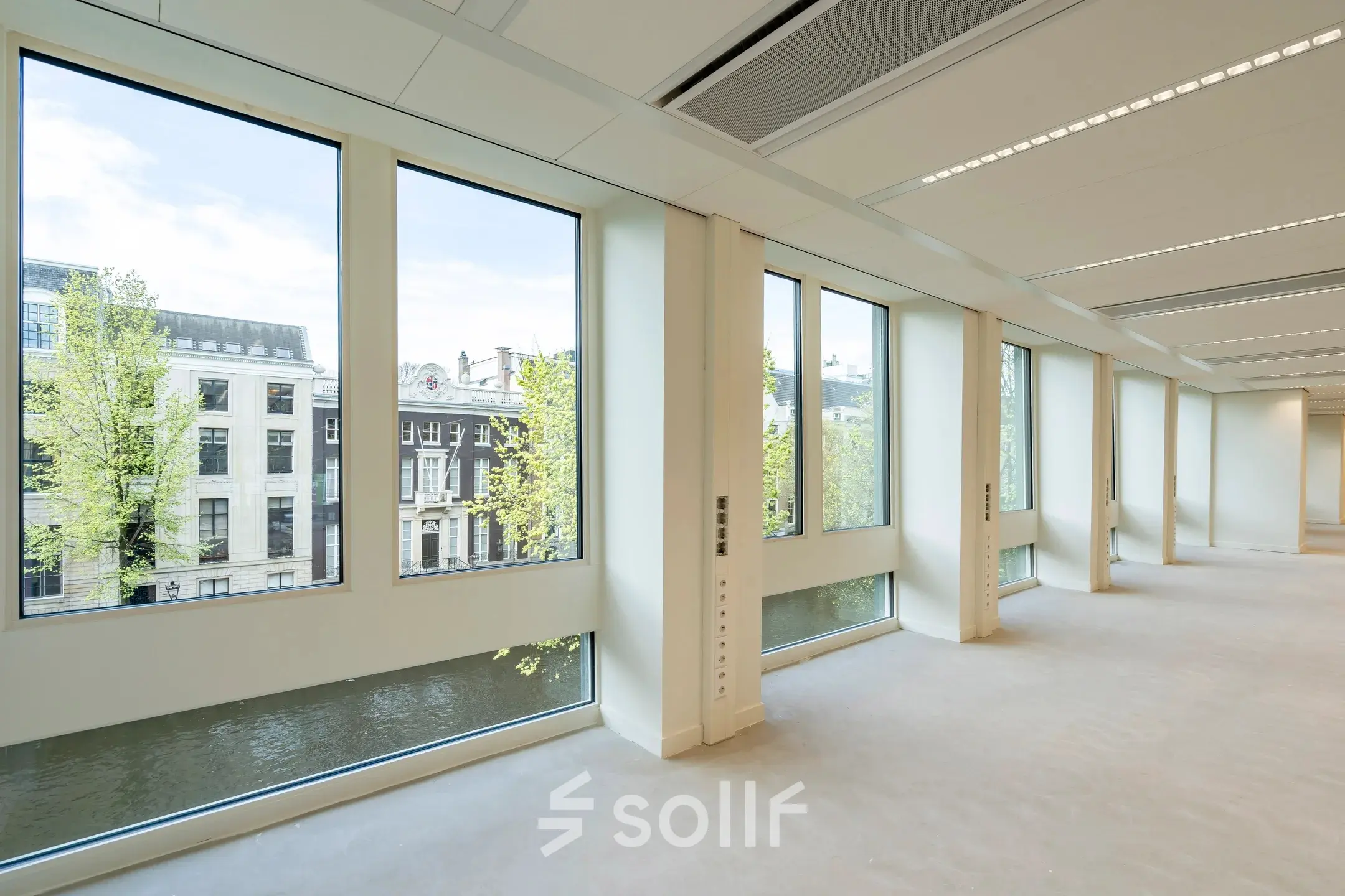 Interior view of an office space rental at Herengracht 459-469, featuring large windows and abundant natural light with canal views in Amsterdam Canal Belt.