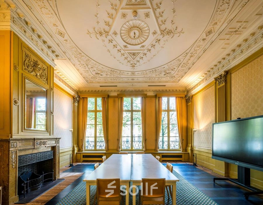 Elegant office space with ornate ceiling and large windows at Herengracht 582-584, Amsterdam Canal Belt, perfect for office space rental. Furnished with a long table and chairs, ideal for meetings.