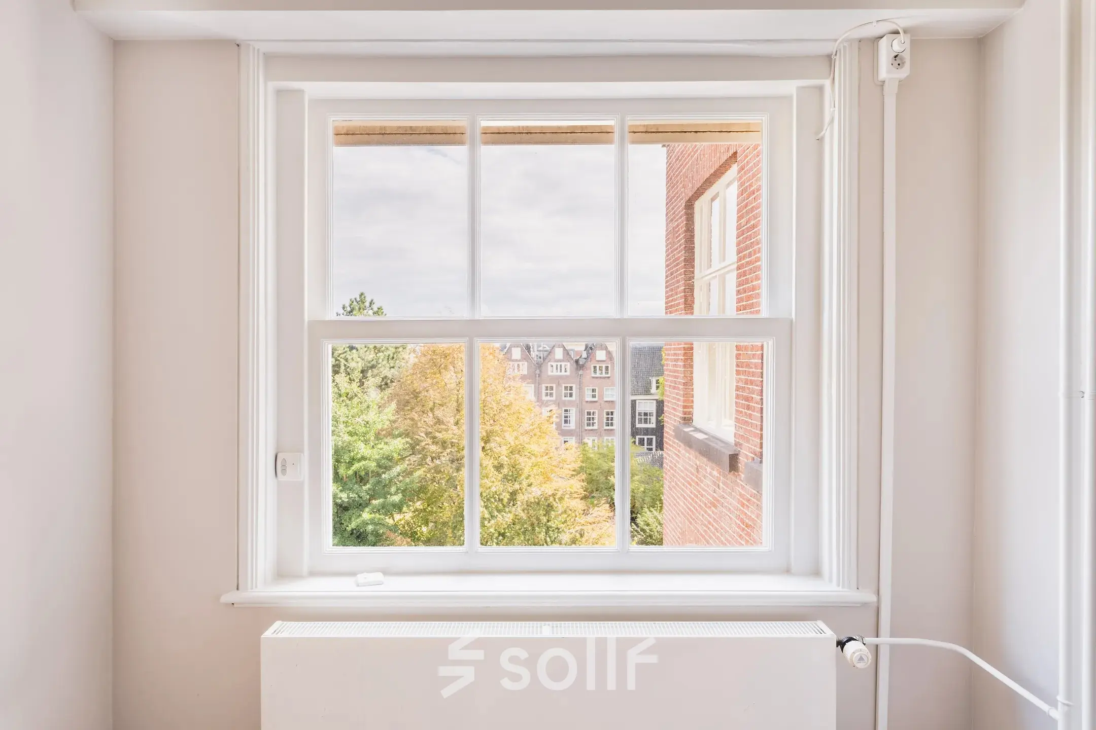 Bright office space rental at Herengracht 582-584 in Amsterdam Canal Belt, featuring a large window with a view of the historic cityscape.