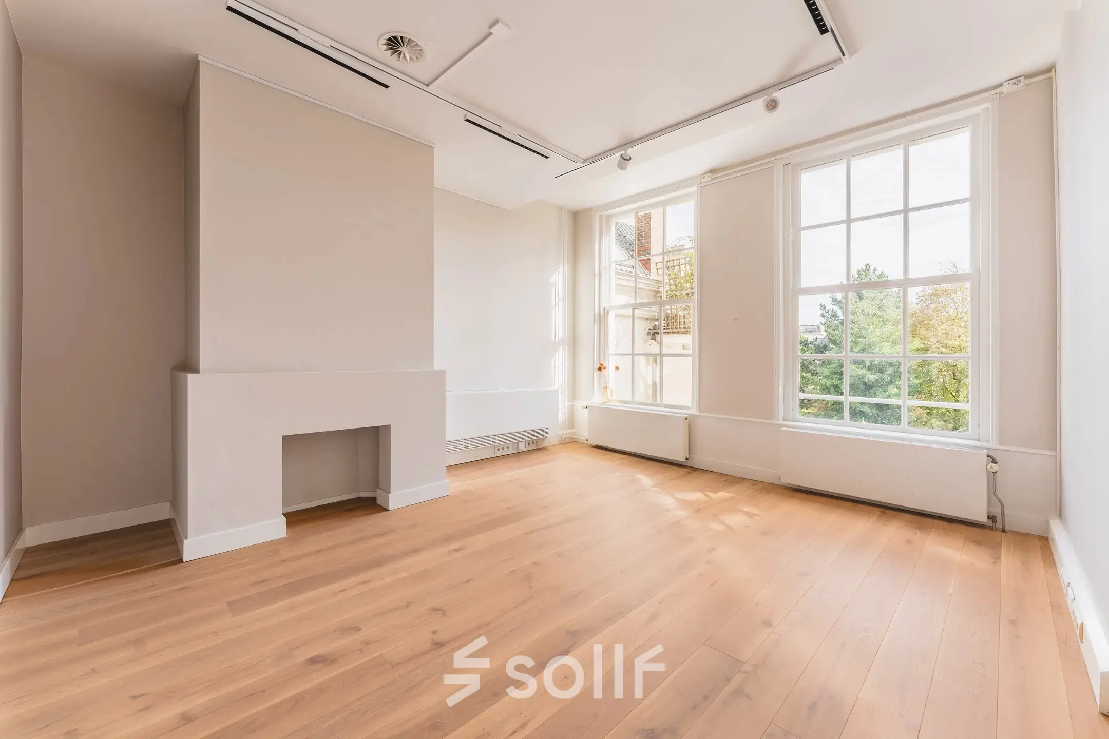 Bright, unfurnished office space with wooden flooring and large windows overlooking the Amsterdam Canal Belt, ideal for office space rental.