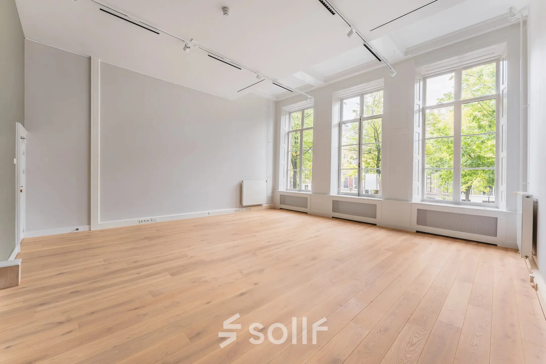 Spacious office to rent at Herengracht 582-584 in the Amsterdam Canal Belt, featuring large windows and wooden flooring, perfect for office space rental.