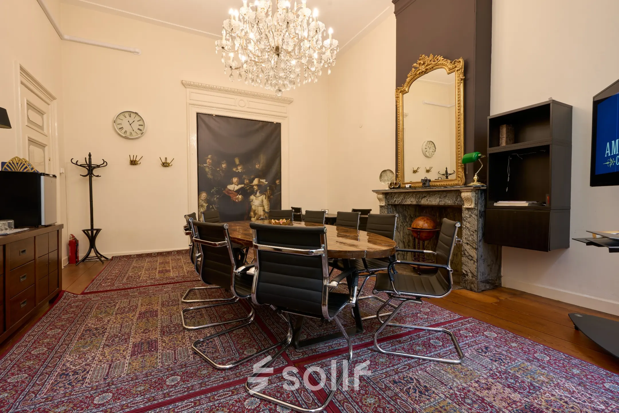 Elegant conference room at Keizersgracht 391A, Amsterdam Canal Belt, available for office space rental with a chandelier, marble fireplace, and sleek chairs around a wooden table.