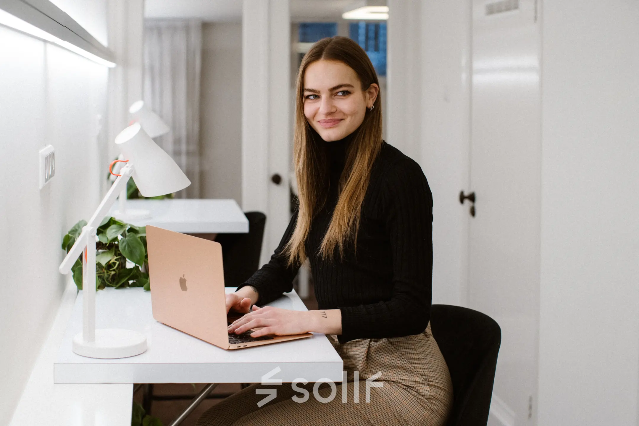Businessperson working on a laptop in a bright office space with modern decor at Keizersgracht 62-64, a sought-after location in Amsterdam Canal Belt for office space rental.