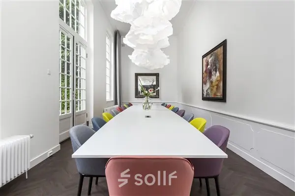 Bright, modern office space rental with a long table and colorful chairs, located at Keizersgracht 62 – 64, Amsterdam Canal Belt.