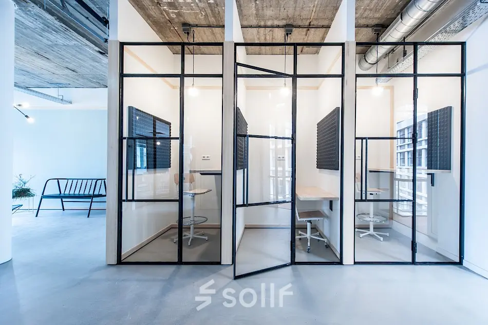 Modern office cubicles for rent at Singel 542, Amsterdam Canal Belt, featuring minimalistic furnishings and industrial design elements.