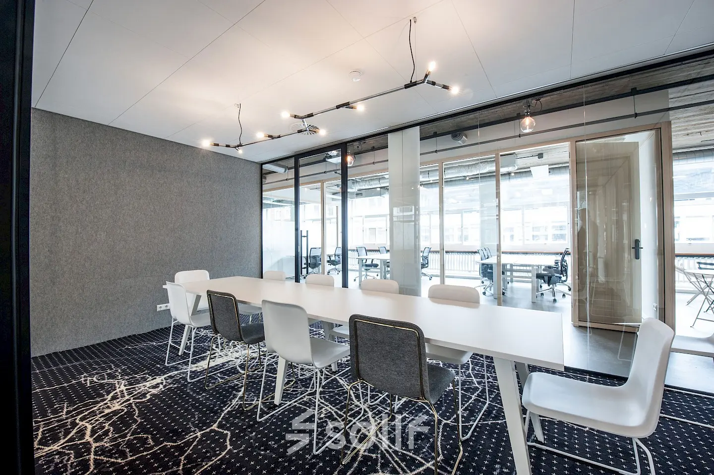 Bright office space with modern furnishings, featuring a long table and chairs, available for rent in Amsterdam Canal Belt.