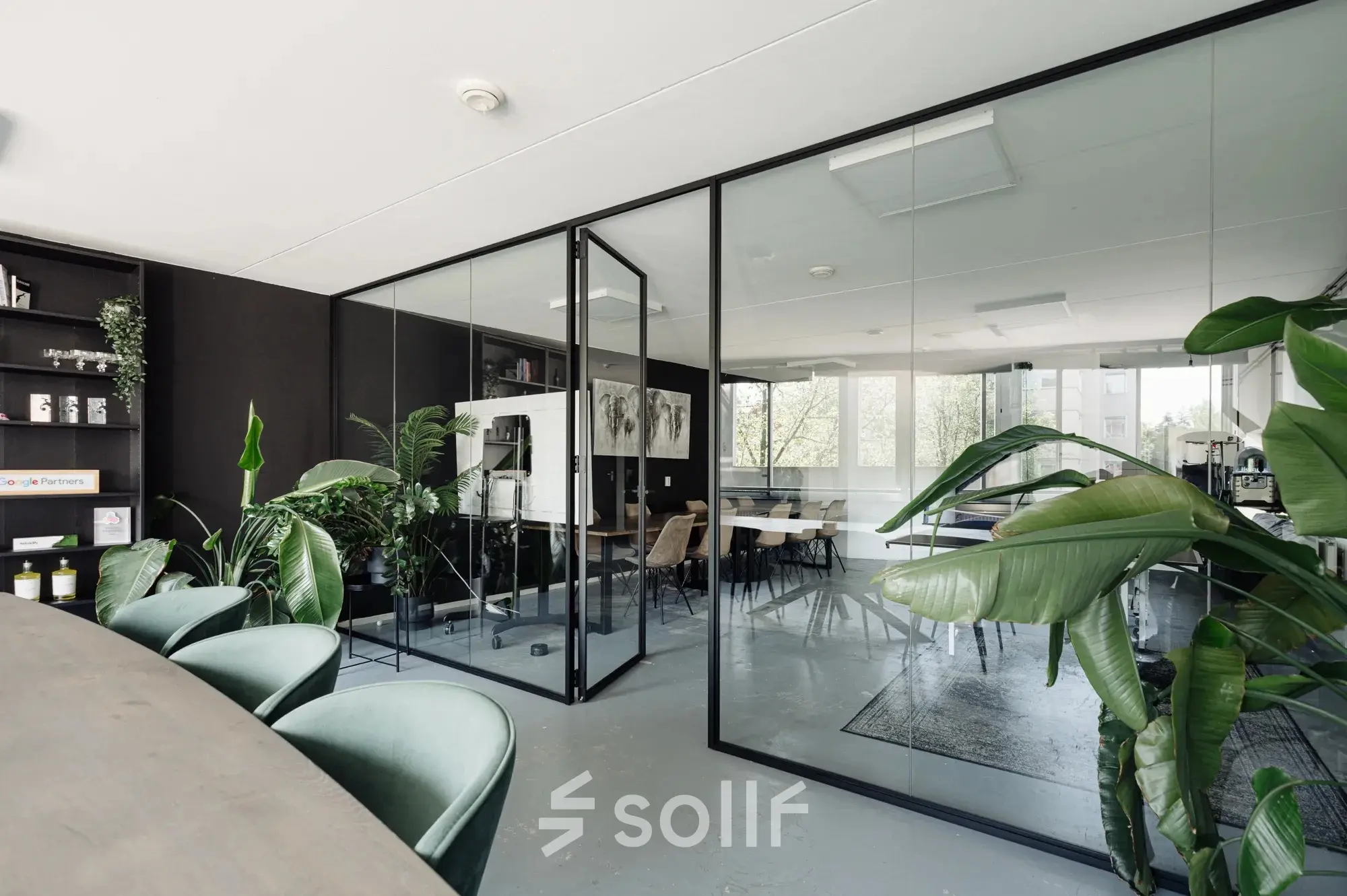 Modern office space rental in Amsterdam Canal Belt with glass partitions, plants, and contemporary furnishings available for rent.