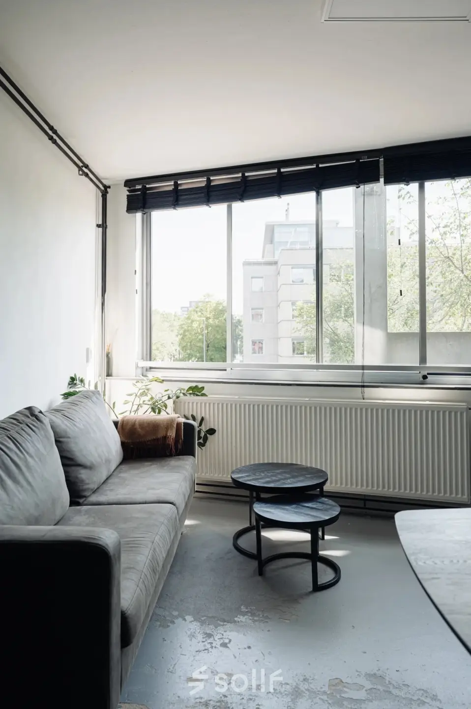 Bright office space with a cozy gray sofa, nested tables, and large windows at Weesperstraat 394-396, perfect for office space rental in Amsterdam Canal Belt.