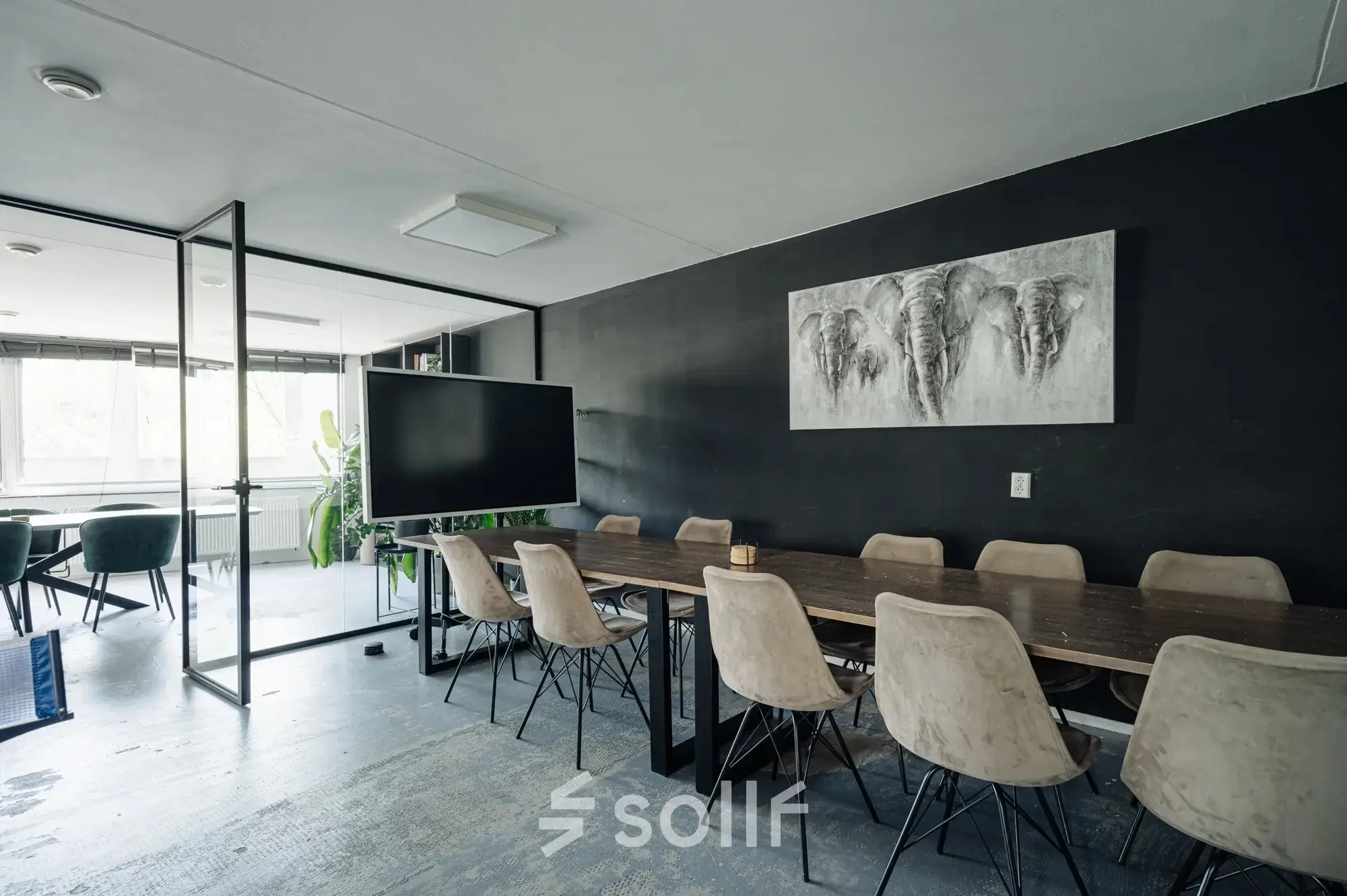 Modern office space with a large wooden table, chairs, and wall artwork at Weesperstraat 394-396, perfect for office space rental in Amsterdam Canal Belt.