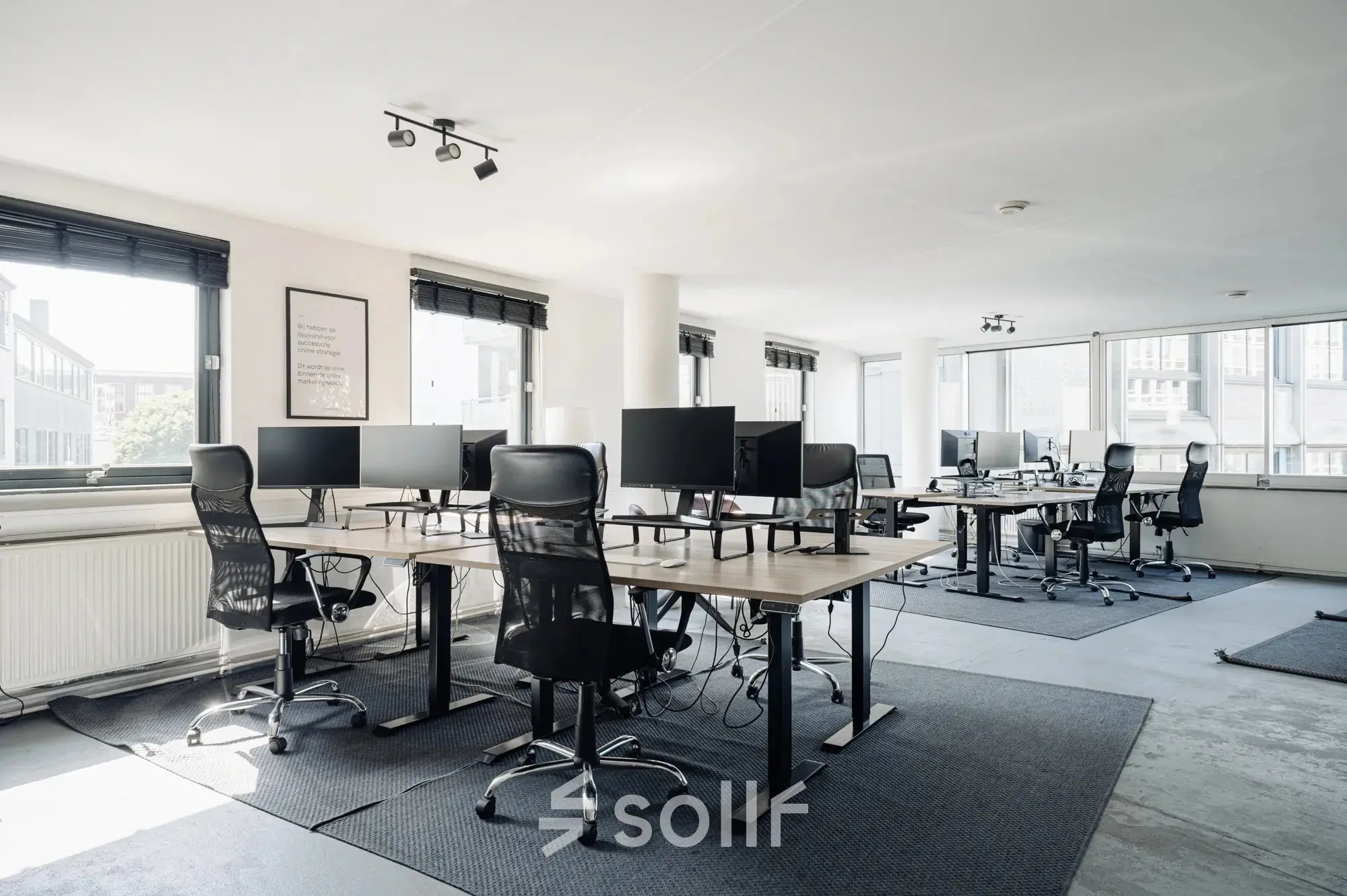 Bright office space at Weesperstraat 394-396, Amsterdam Canal Belt, featuring furnished workstations and large windows offering ample natural light. Ideal for those seeking office space rental in a strategic location.