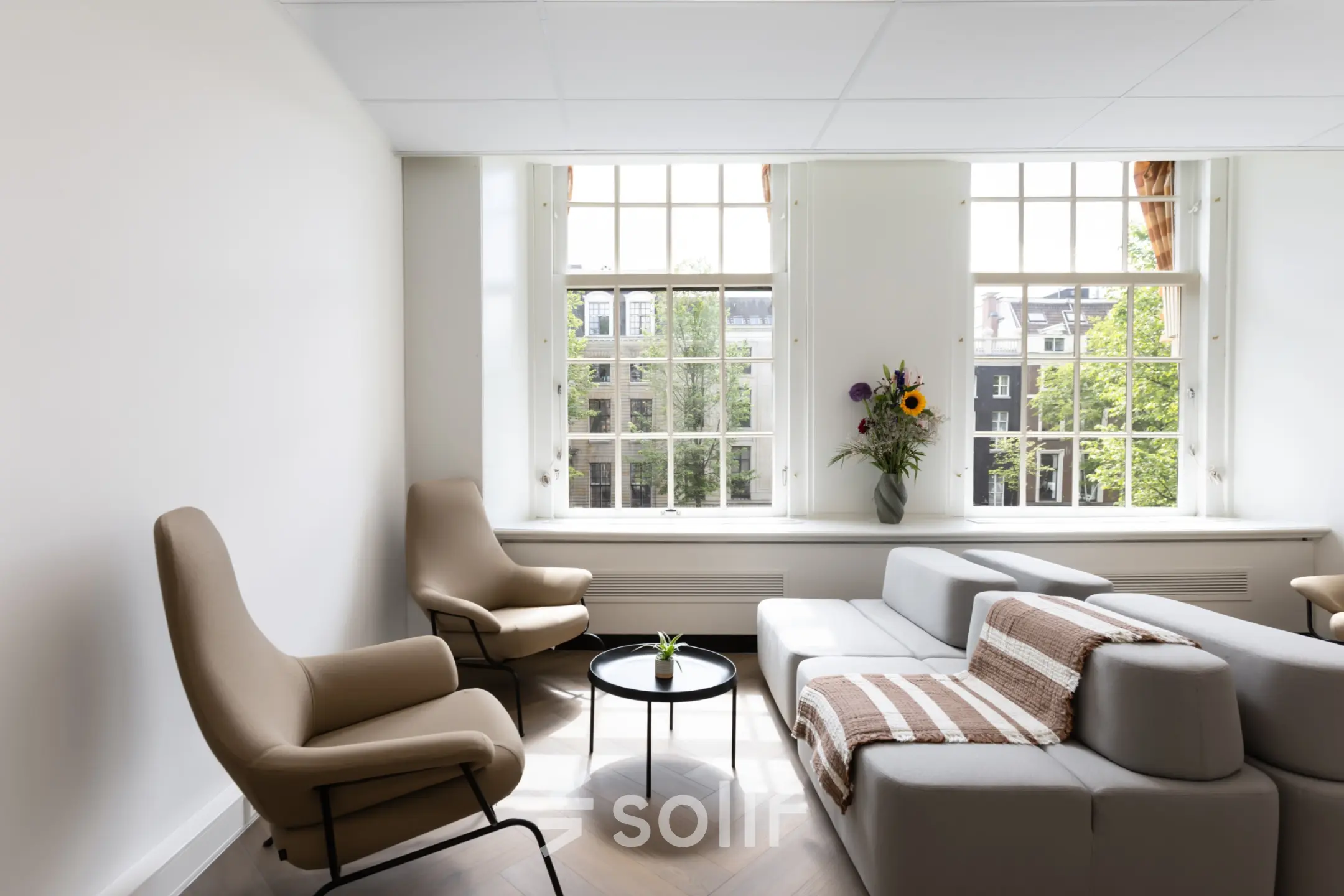 Bright and inviting office space for rent in Amsterdam Center with modern furnishings and large windows overlooking the cityscape.