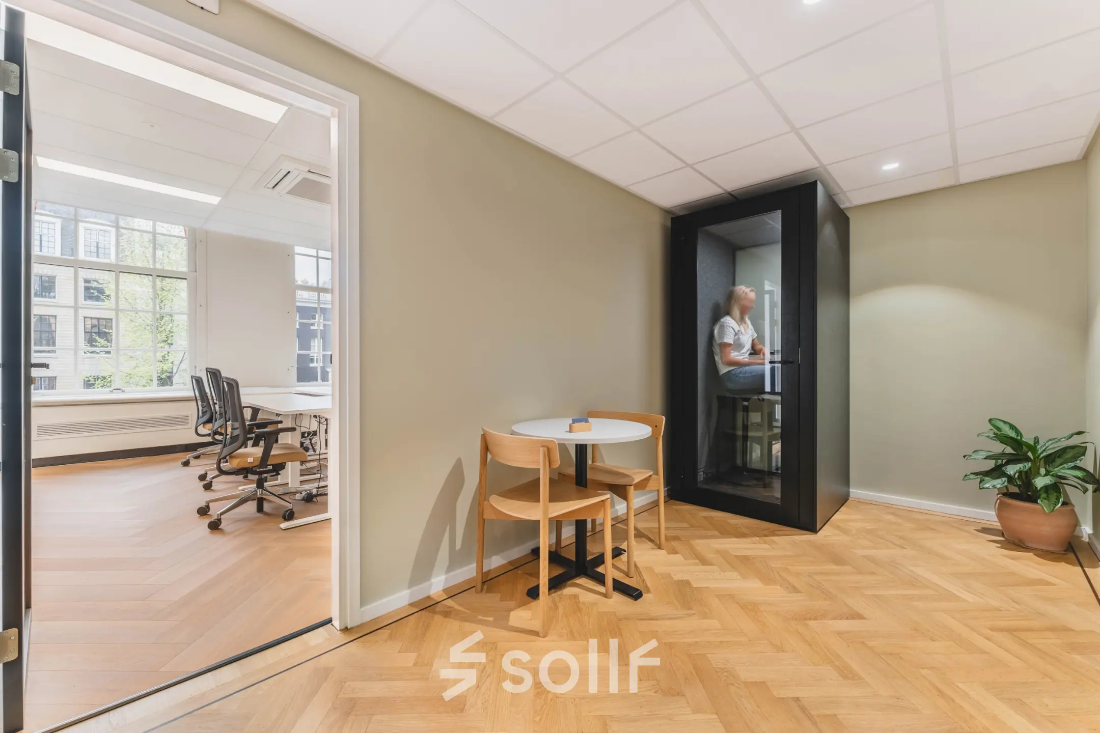 A furnished interior office space at Herengracht 471, Amsterdam Center, featuring a meeting booth and desk, ideal for office space rental.