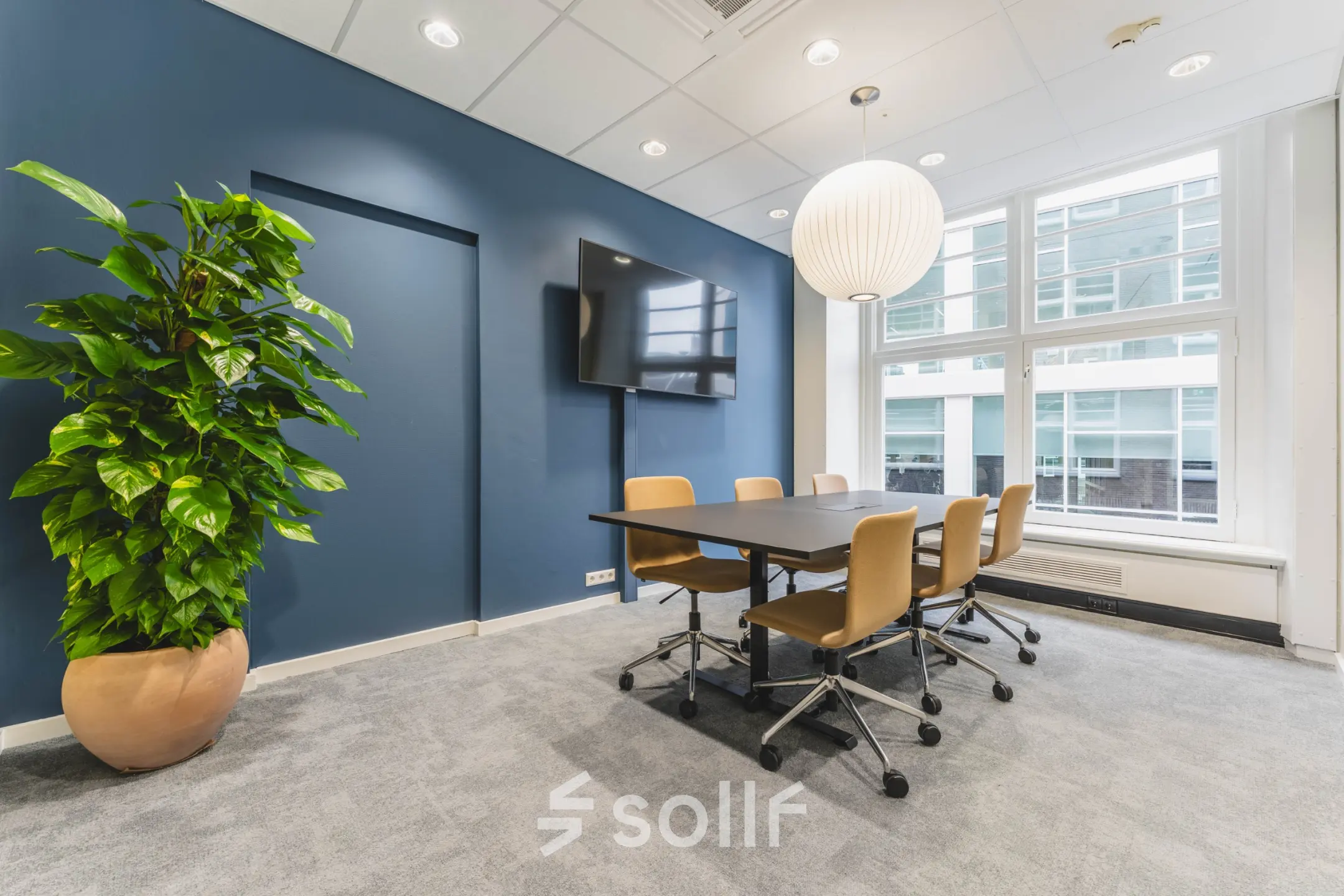 Modern office space at Herengracht 471, Amsterdam Center with a conference table, chairs, and a large screen, perfect for office space rental.