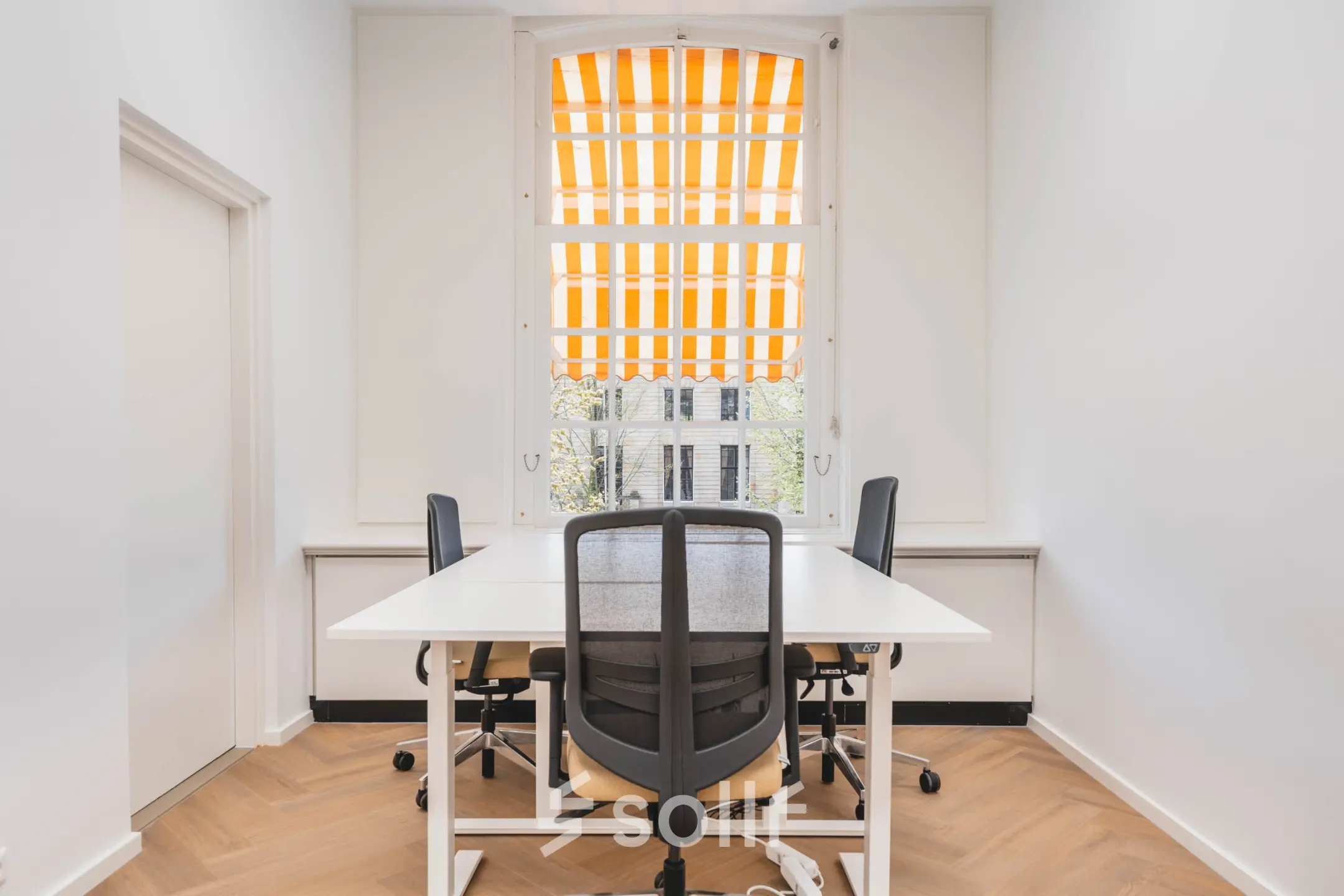 Bright office space with desks and chairs, located at Herengracht 471, Amsterdam Center, available for rent. Ideal for small teams.