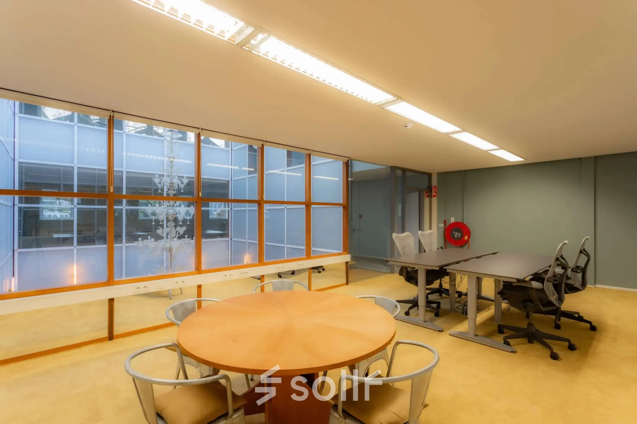 Bright office space for rent at Kerkstraat 204, Amsterdam Center, featuring large windows, desks, and chairs. Ideal for collaborative work.