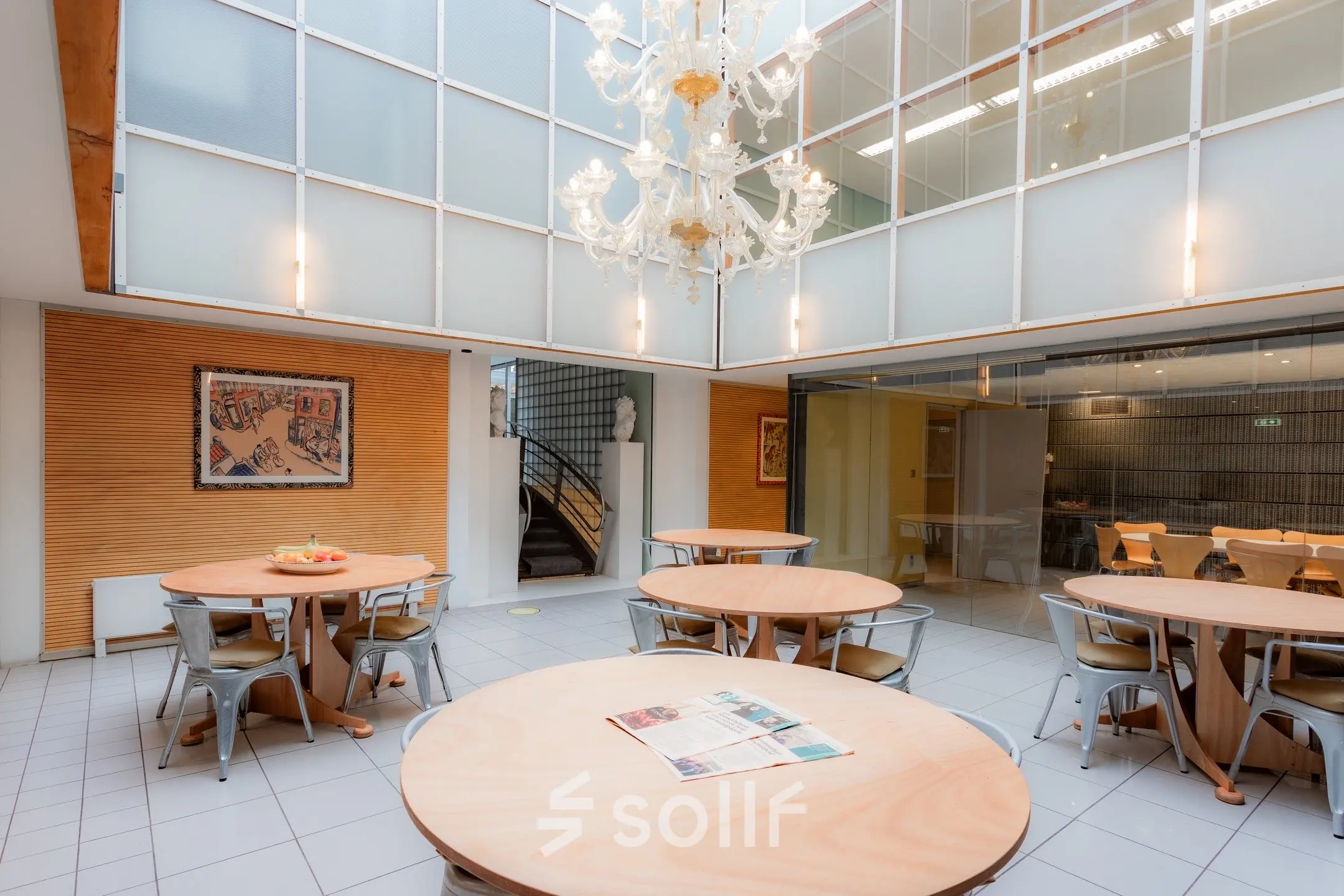 Spacious furnished office space for rent at Kerkstraat 204, Amsterdam Center, featuring round tables and a chandelier, ideal for collaborative work.