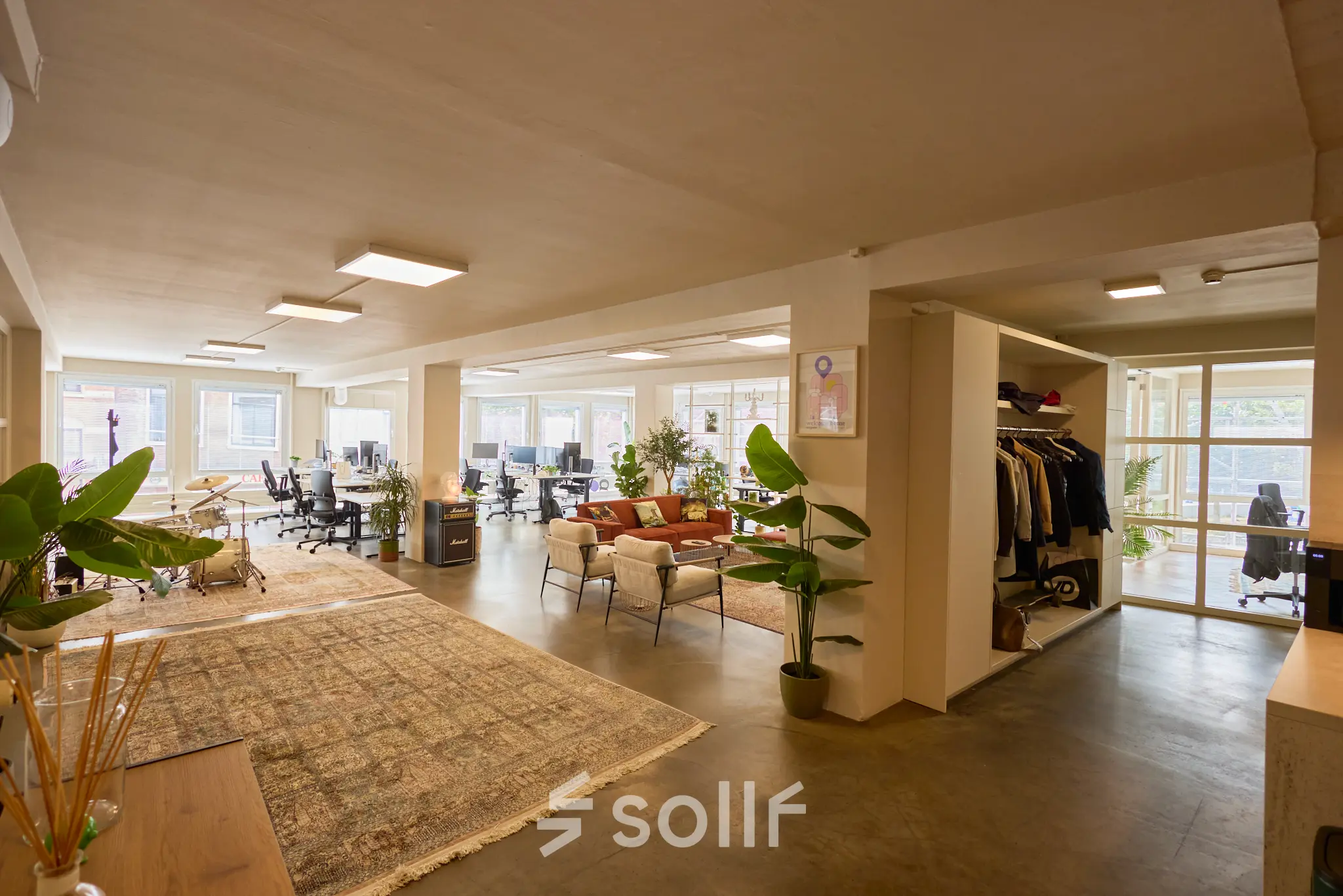 Bright and inviting office space with plants, desks, and a lounge area, ideal for rent in Amsterdam Center.
