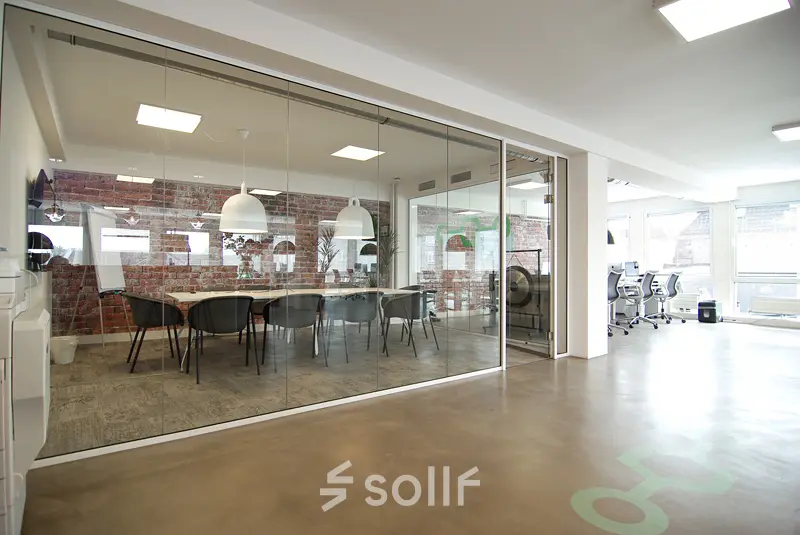 Modern office space at Kleine Gartmanplantsoen 21 in Amsterdam Center featuring glass-walled conference room and open workspaces, perfect for office space rental.