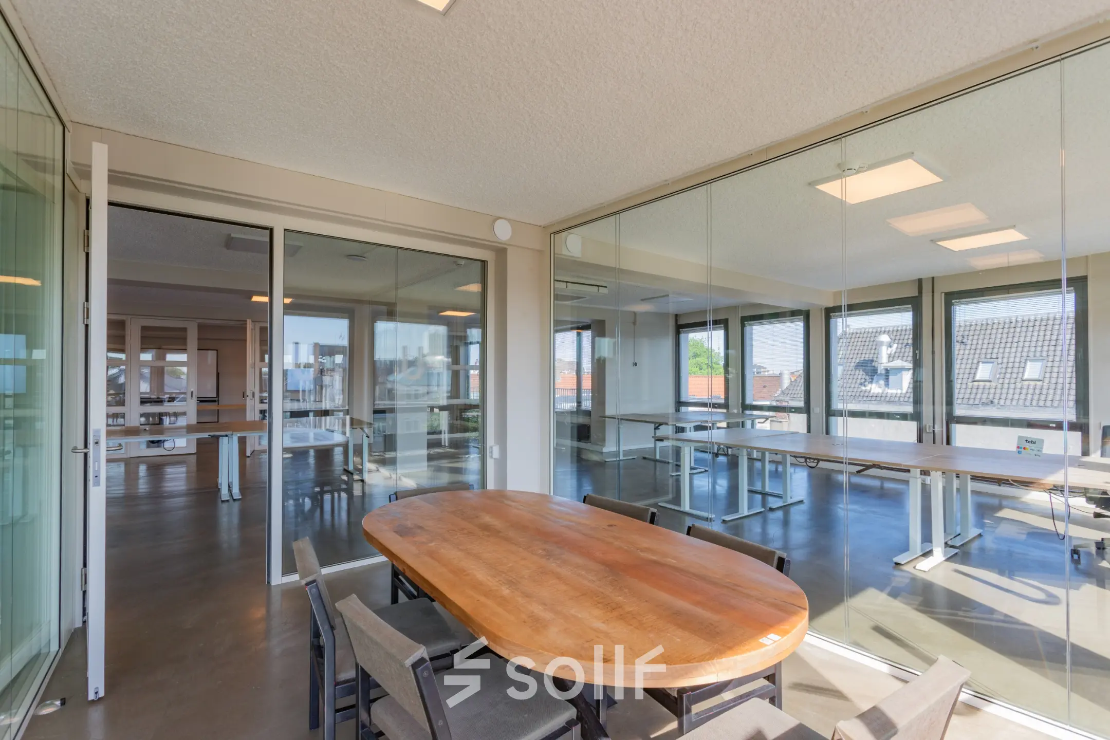 Bright office space with large wooden table and chairs, surrounded by glass walls, perfect for office space rental at Kleine Gartmanplantsoen 21 in Amsterdam Center.