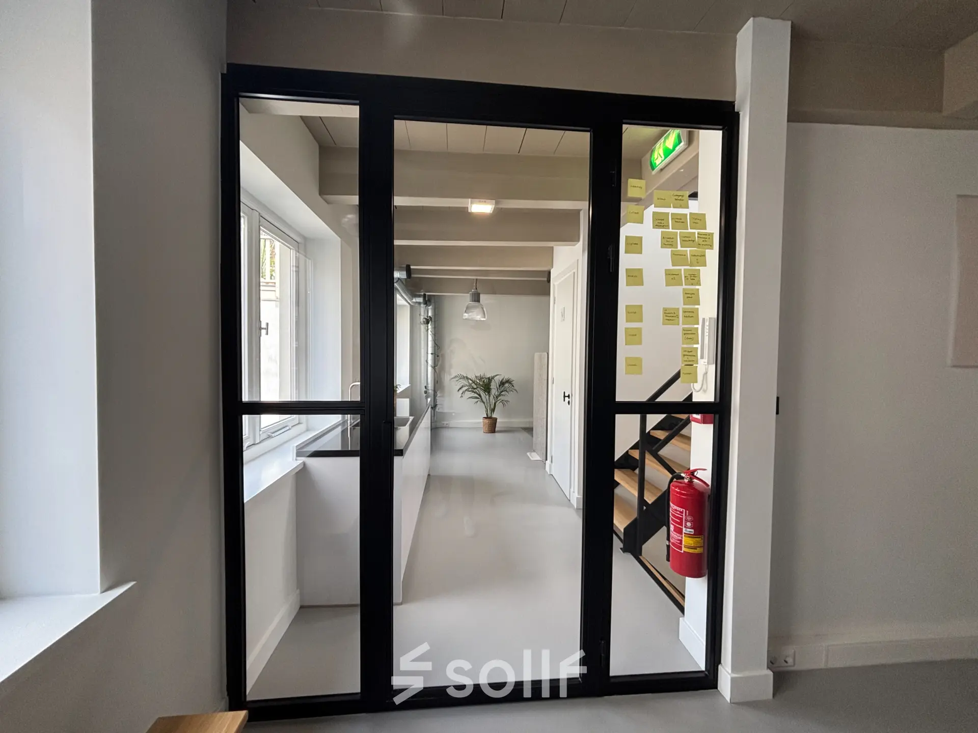 A modern office space to rent at Kloveniersburgwal 131K, Amsterdam Center. The interior is furnished with a sleek glass door, natural light, and contemporary design elements.