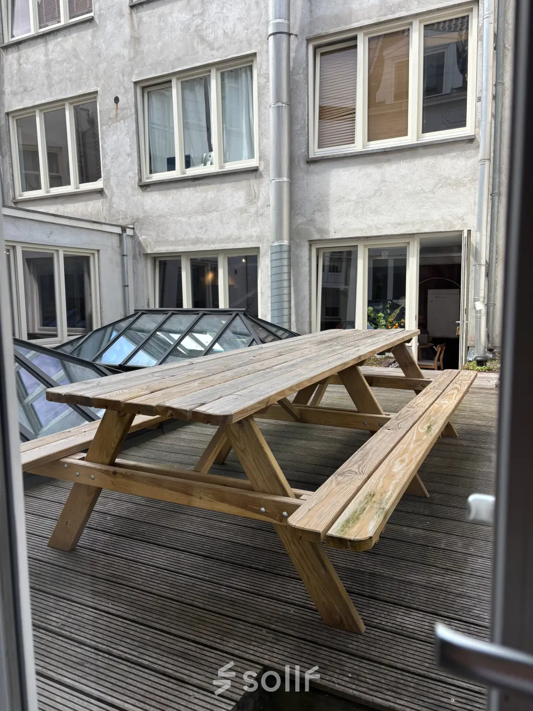 Outdoor wooden picnic tables on a deck outside an office space for rent at Kloveniersburgwal 131K in Amsterdam Center.