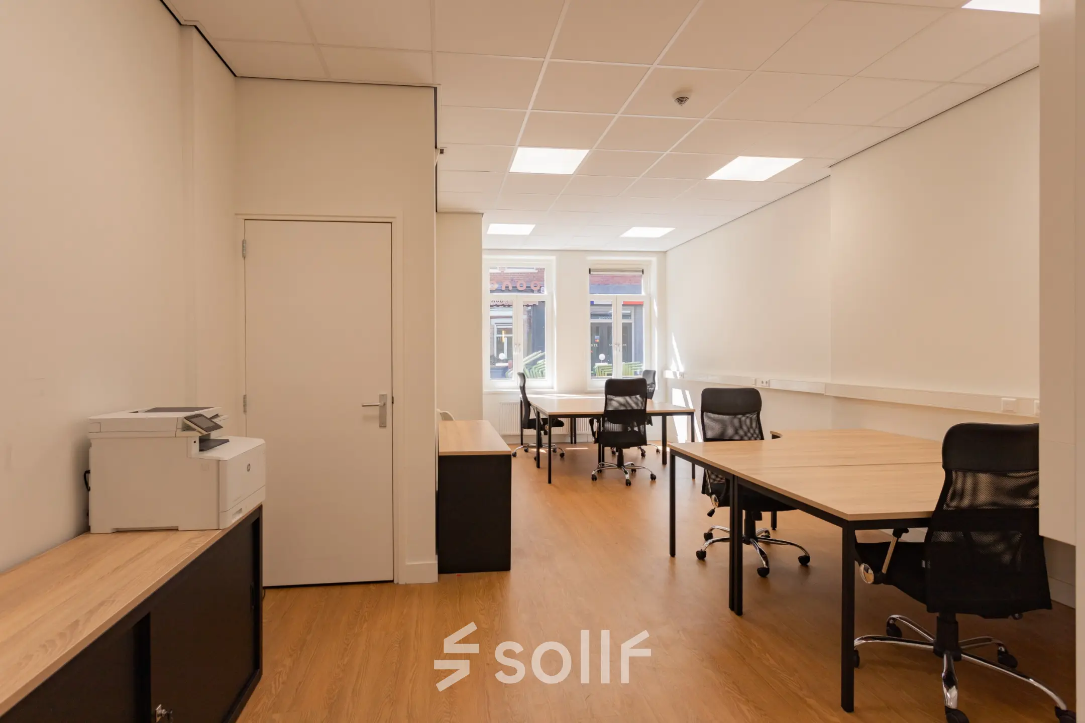 Bright office space at Korte Leidsedwarsstraat 133A 133A, Amsterdam Center featuring wooden floors, office desks with chairs, and a printer. Ideal for rent as a workspace.