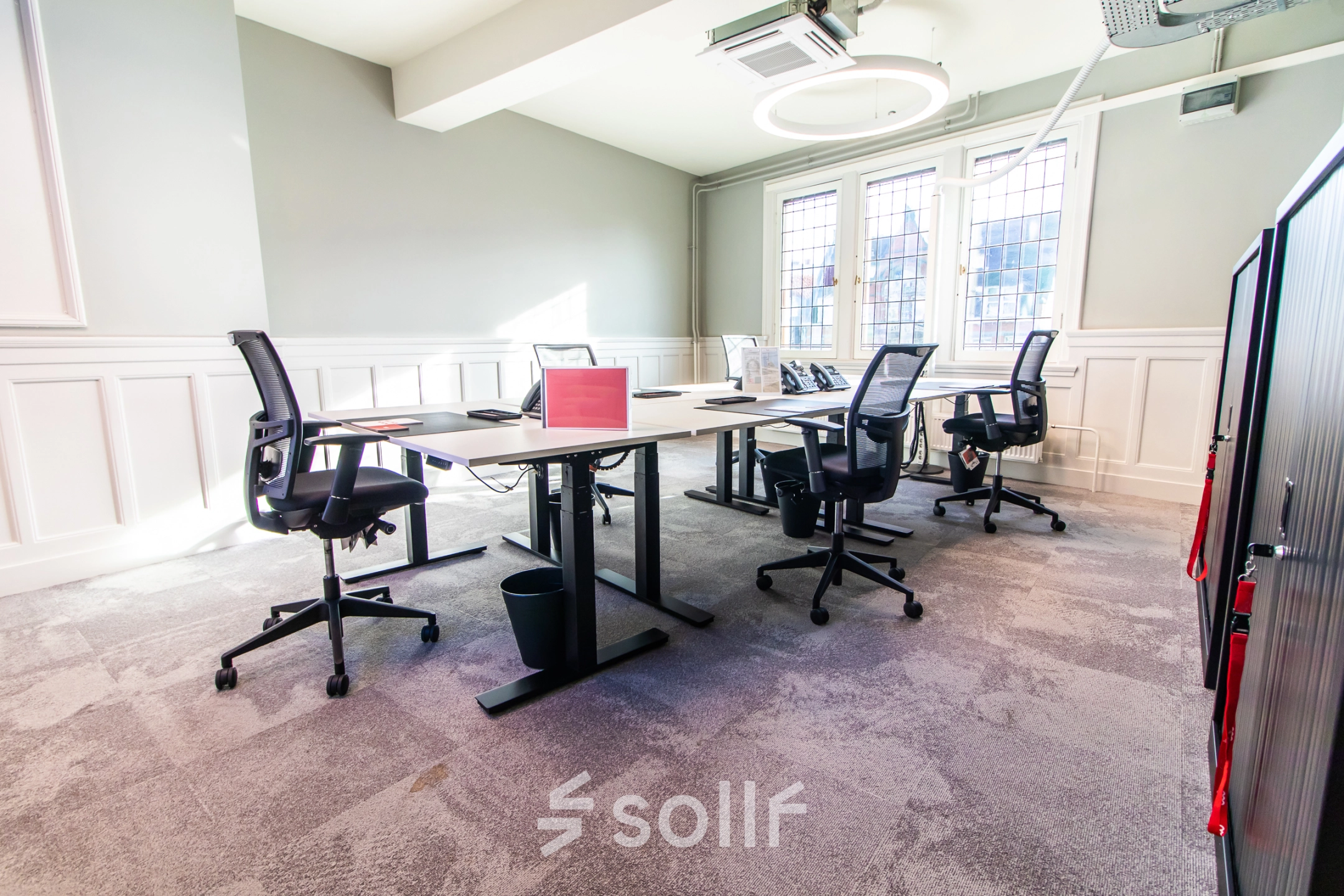 Furnished office space with multiple desks and chairs, located in Amsterdam Center. Ideal for office space rental with natural light and modern decor.