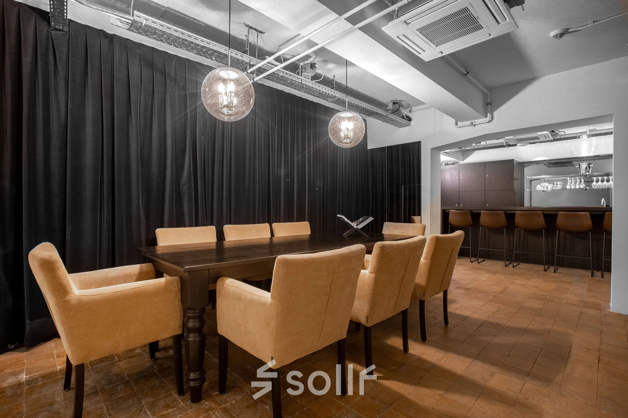 Elegant office space available for rent at Nieuwezijds Voorburgwal in Amsterdam Center, featuring a meeting area with a long wooden table and seating, adjacent to a stylish bar section.
