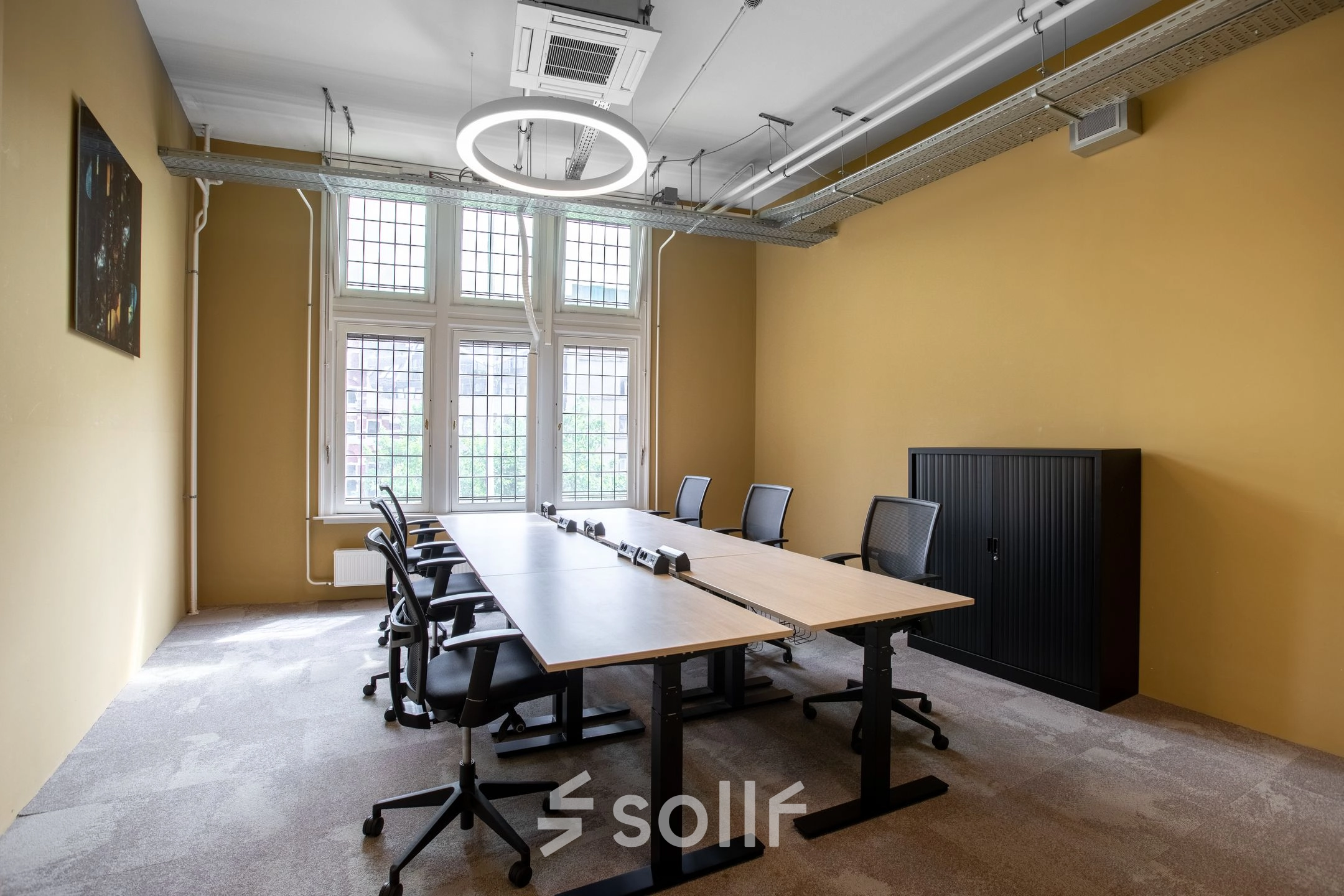 Bright office space at Nieuwezijds Voorburgwal 104-108 in Amsterdam Center, featuring a large table and chairs ideal for meetings or collaborative work, available for office space rental.