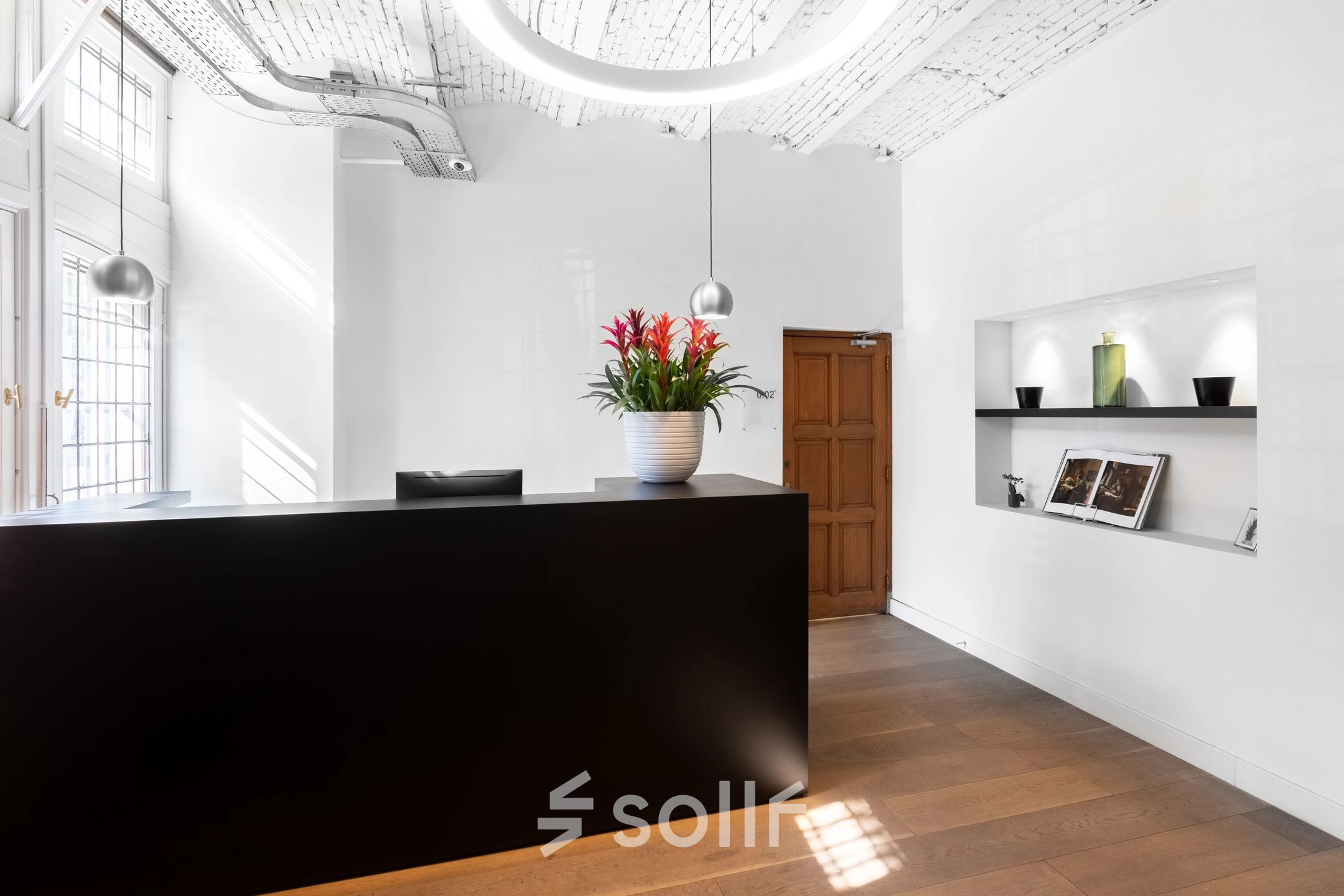 Modern office reception with a sleek black desk at Nieuwezijds Voorburgwal 104-108 in Amsterdam Center, ideal for office space rental.