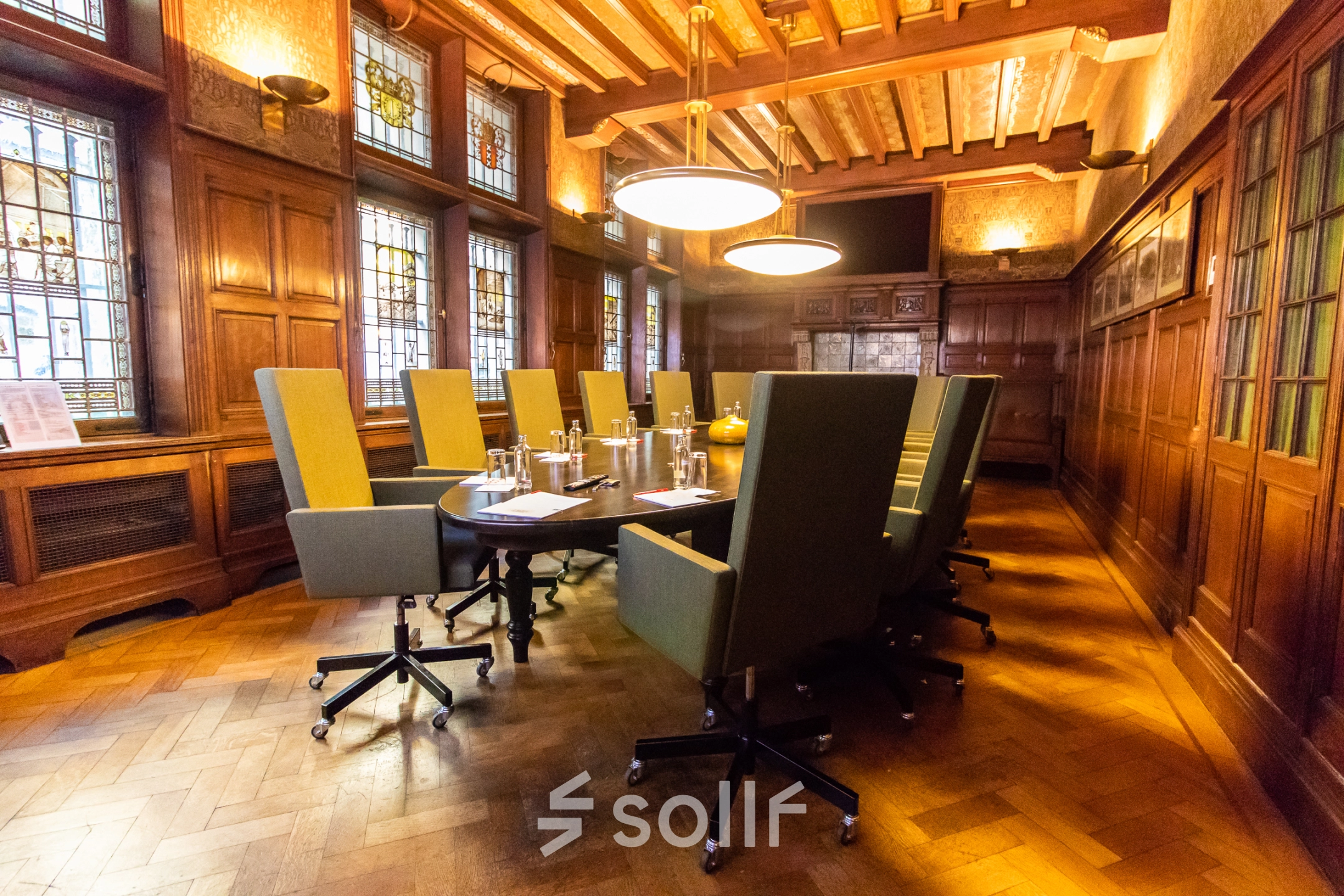 Elegant conference room with high-backed chairs around a long table, featuring wood-paneled walls and stained glass windows in Amsterdam Center.