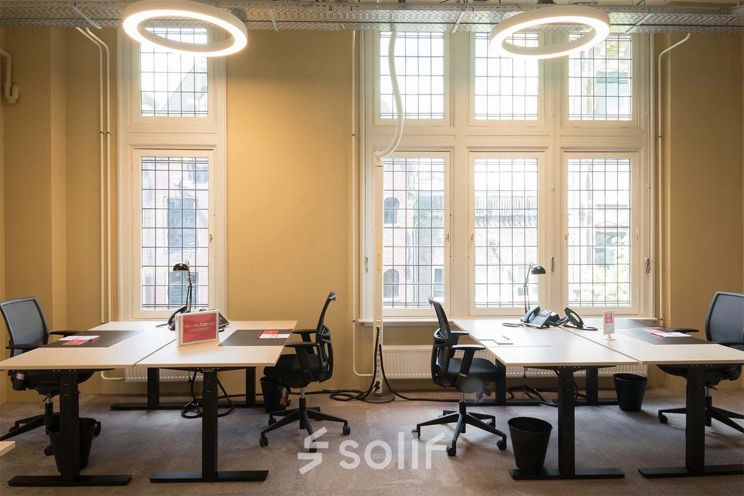 Bright office space with large windows and modern desks at Nieuwezijds Voorburgwal 104-108, Amsterdam Center, perfect for those seeking an office space rental.
