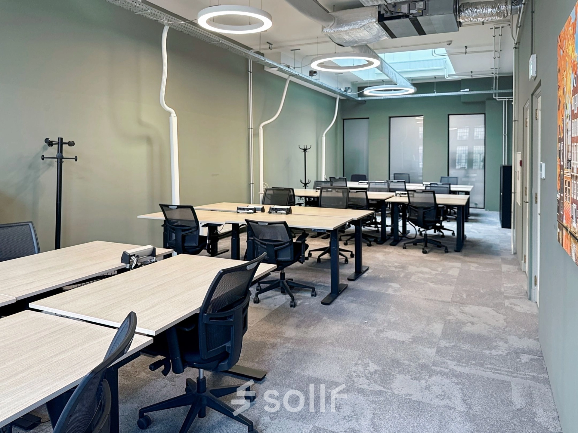 Modern office space available for rent at Nieuwezijds Voorburgwal 104-108, Amsterdam Center, featuring multiple desks and ergonomic chairs under stylish lighting in a well-lit interior.