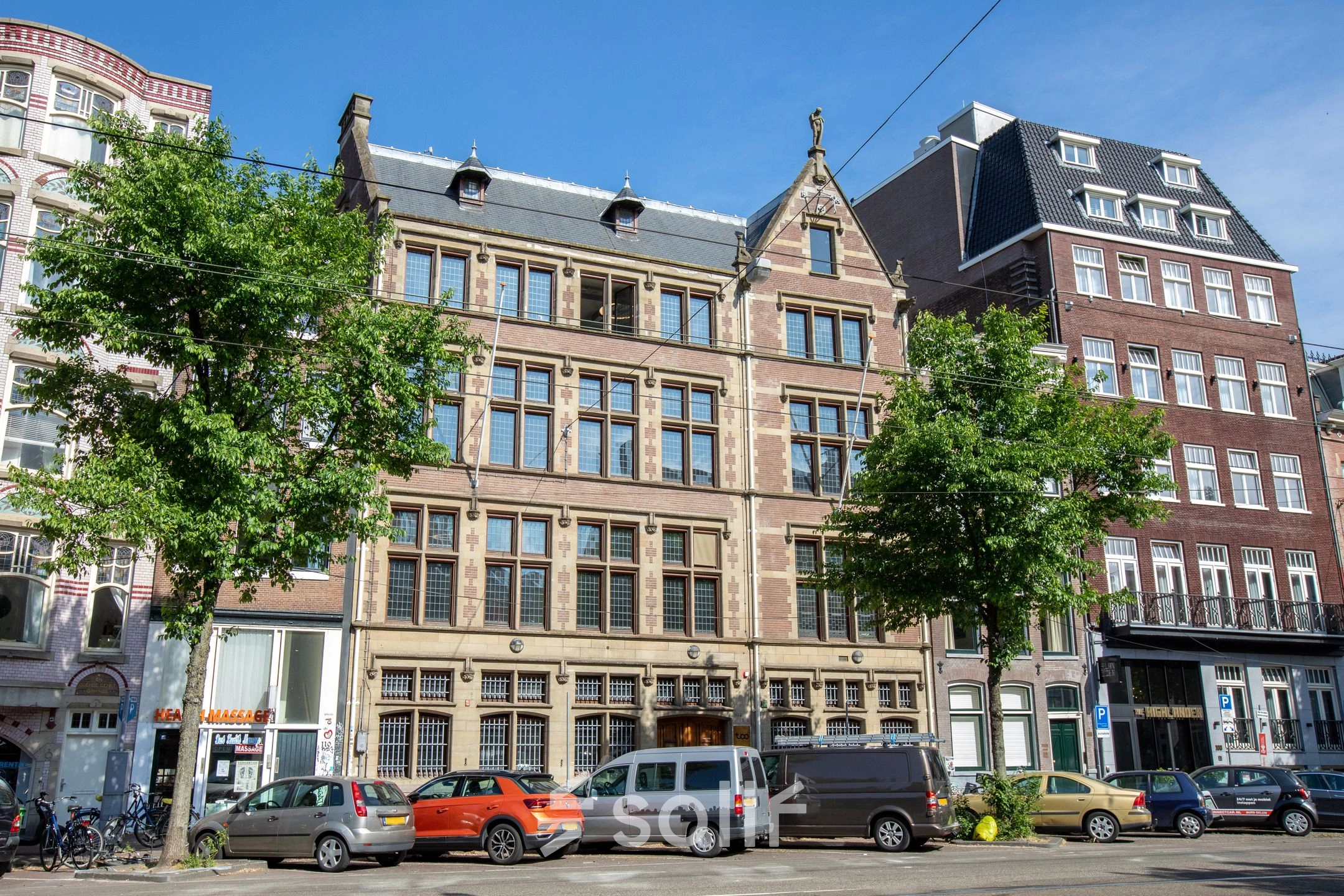Exterior view of the office building at Nieuwezijds Voorburgwal 104-108, located in Amsterdam Center, showcasing a historic façade with several parked cars.