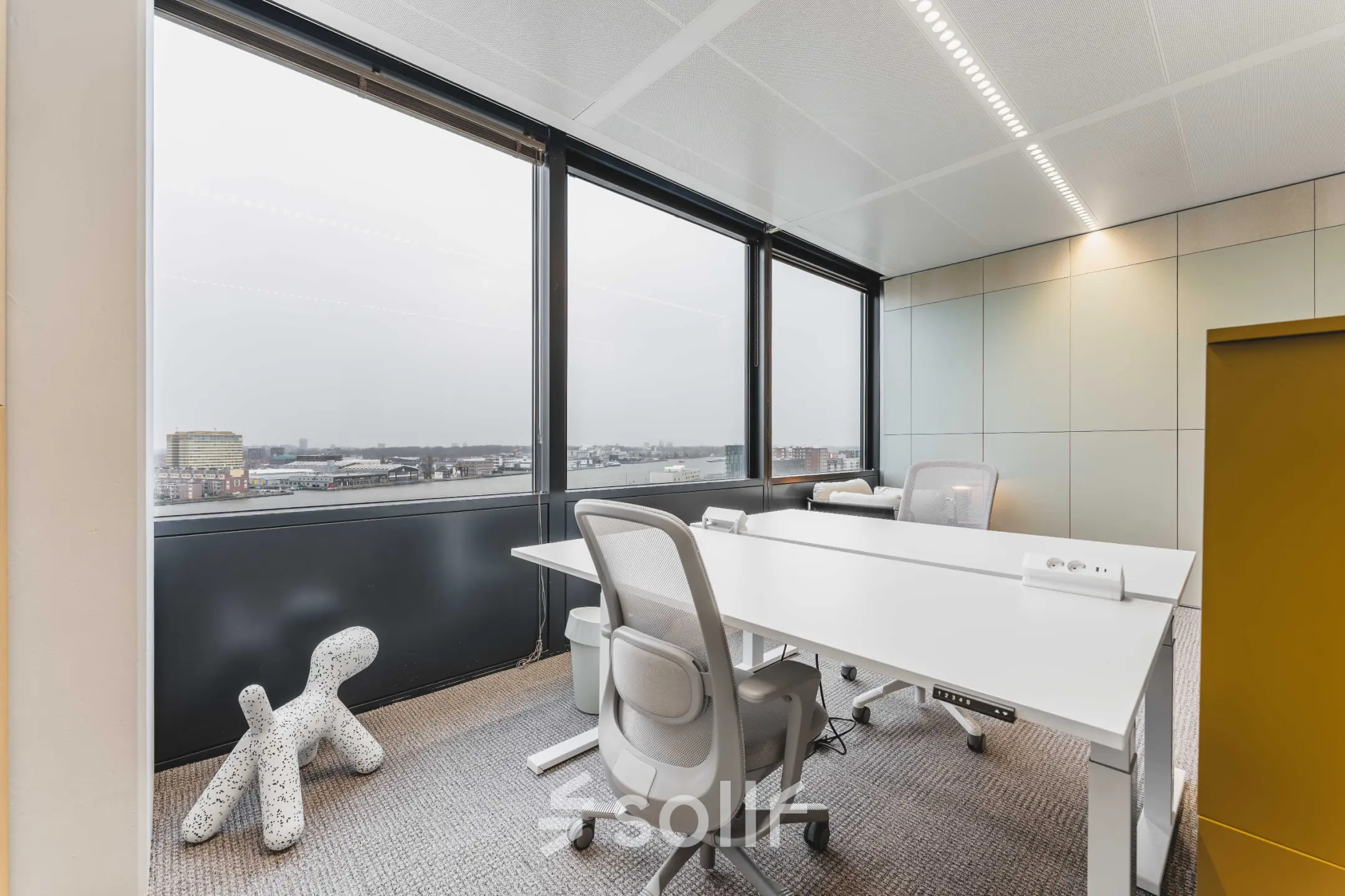 Bright office space featuring large windows and modern furniture with views of Amsterdam Center, perfect for office space rental.
