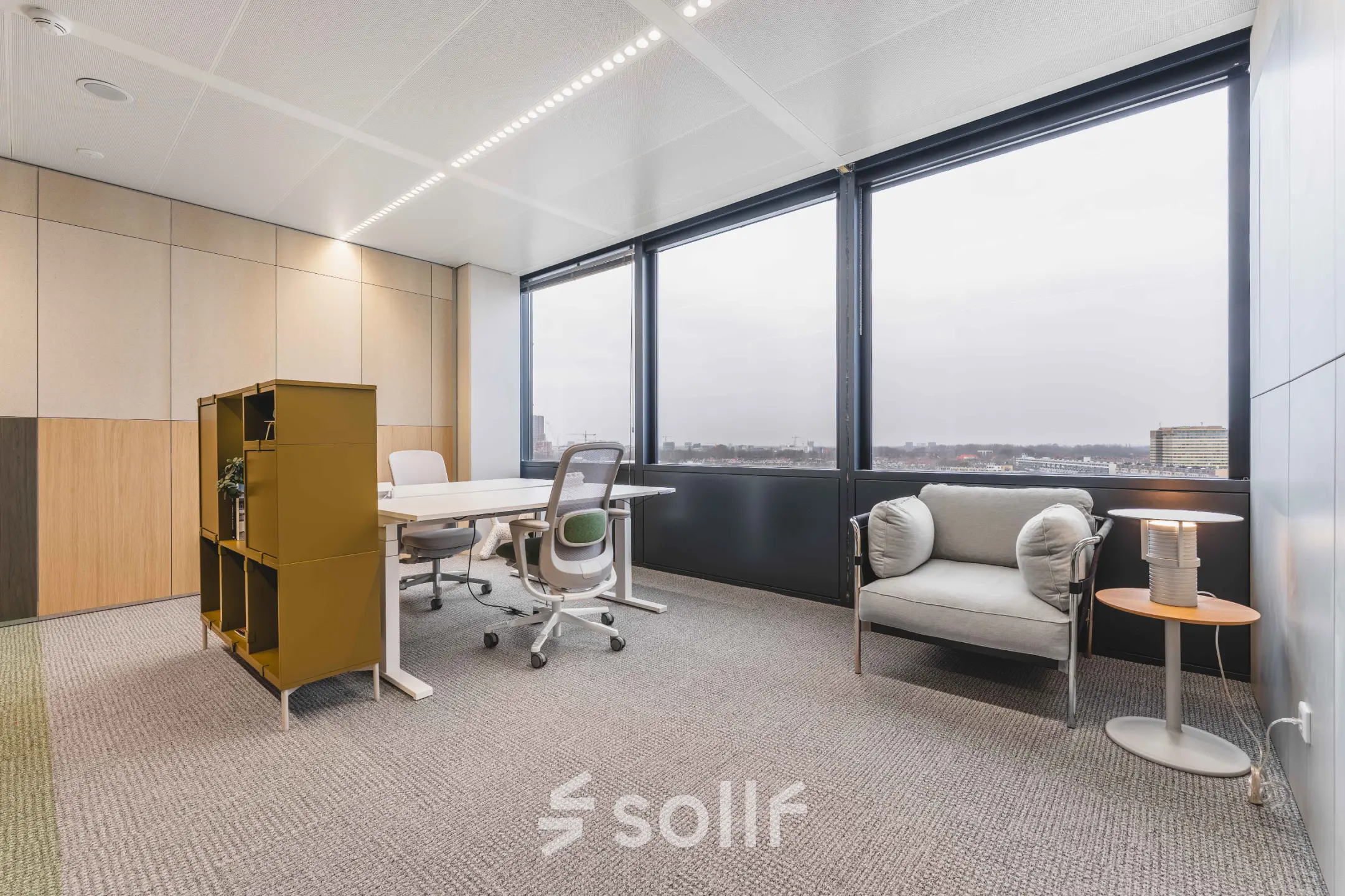 Bright office space with large windows at Piet Heinkade 55, ideal for those seeking an office to rent in Amsterdam Center. Includes a desk, chairs, and storage unit.