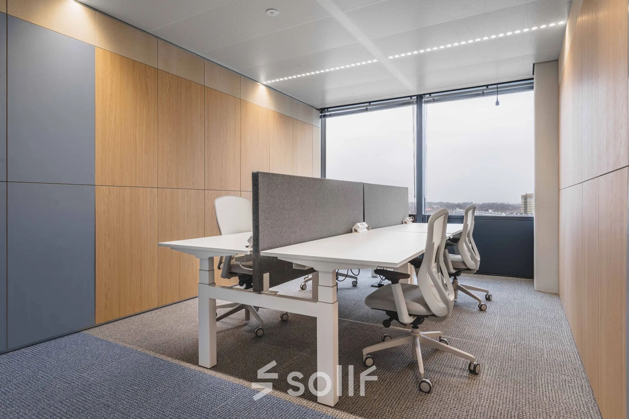 Furnished office space at Piet Heinkade 55, Amsterdam Center, featuring modern workstations with ergonomic chairs and a view through large windows.