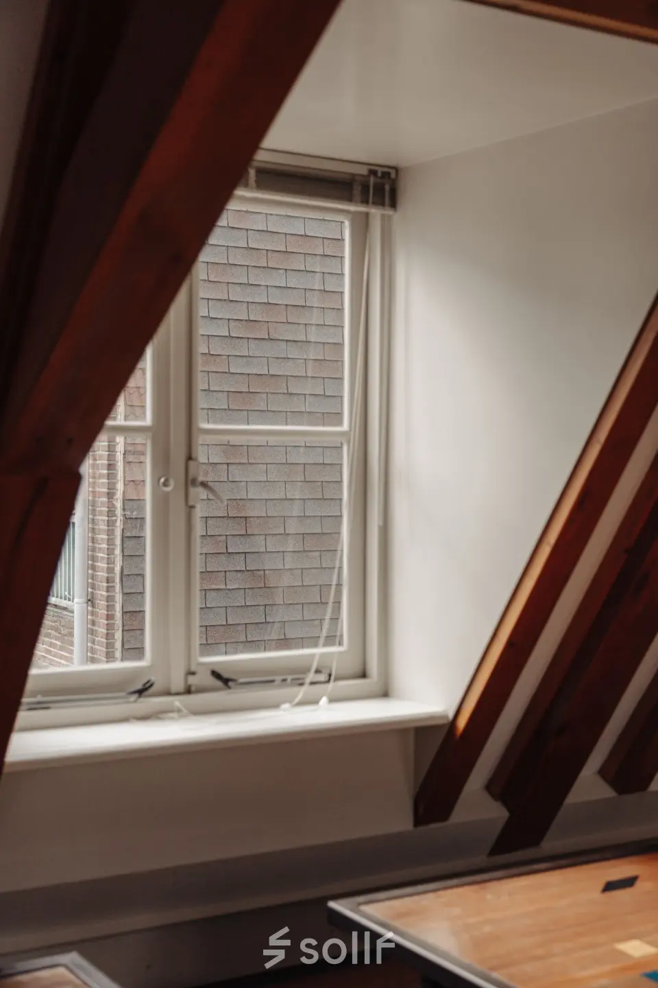 Interior view of office with a slanted ceiling and a window at Prins Hendrikkade 14, Amsterdam Center, ideal for those seeking office space rental with character.