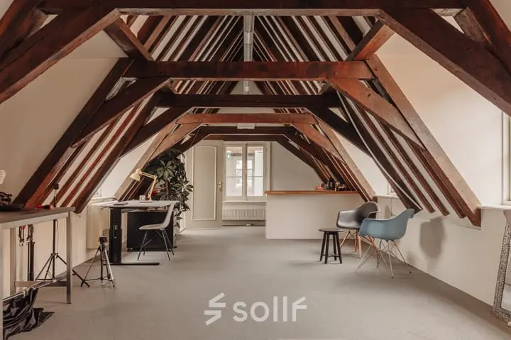 Cozy office space under wooden beams at Prins Hendrikkade 14, Amsterdam Center, available for office space rental, with modern furnishings including chairs and desks.